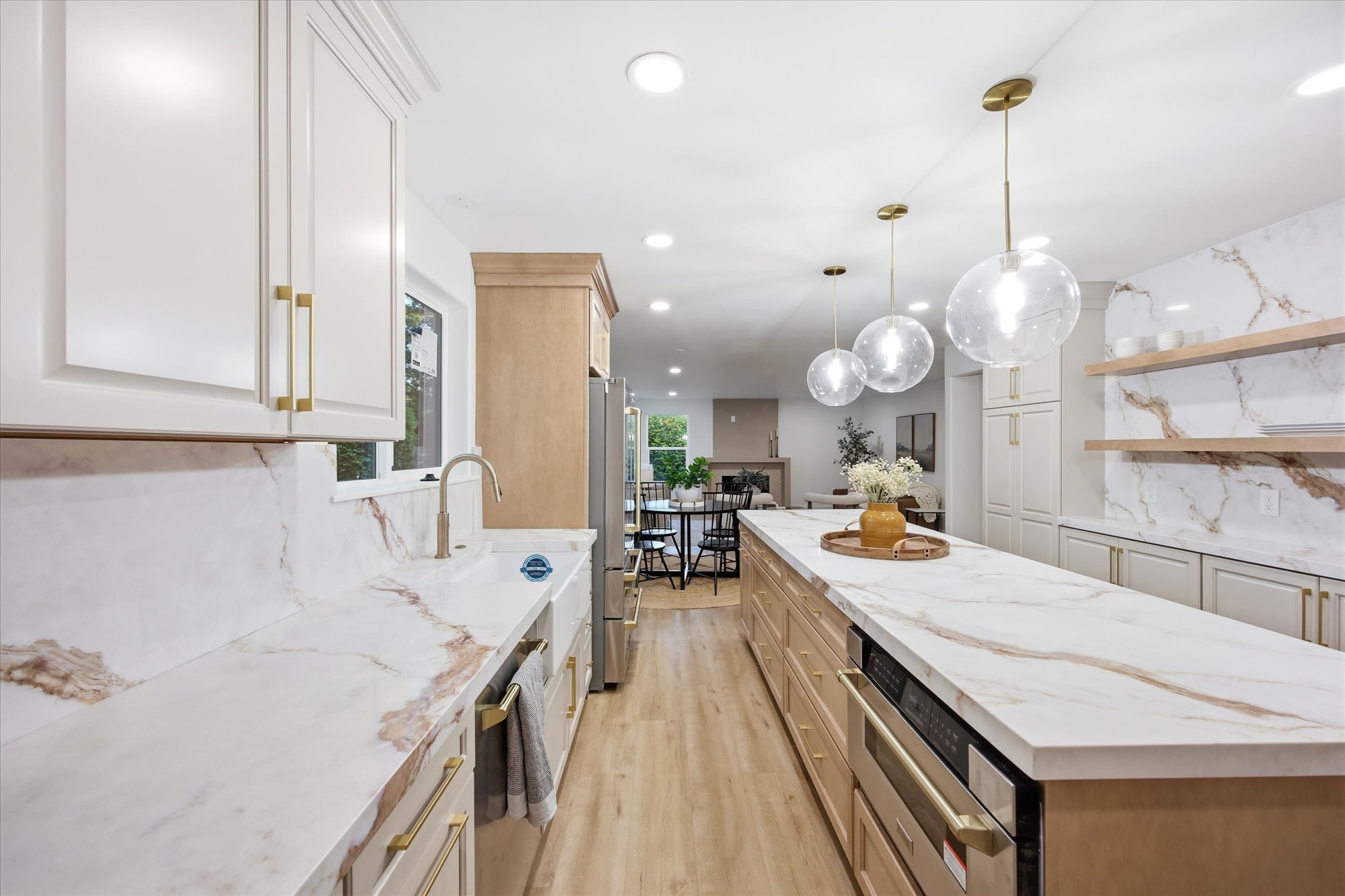 Kitchen featuring an expansive island with a stone countertop, three spherical pendant lights, and integrated appliances