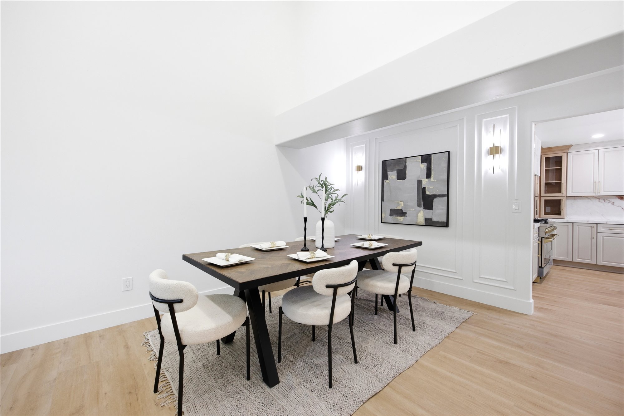 Dining space featuring light wood-finish flooring, white paneled wall detailing, and dual sconce lighting fixtures