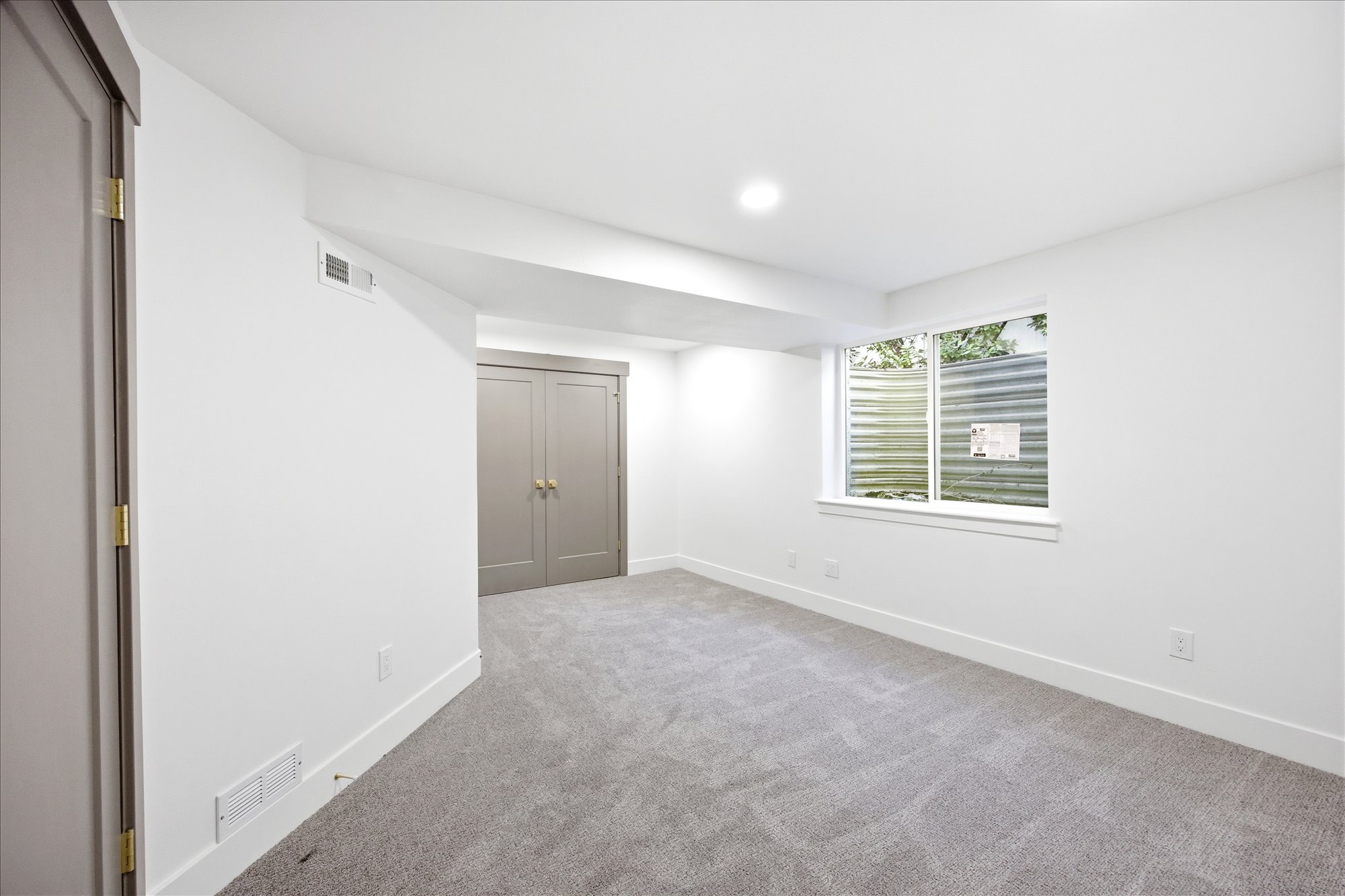 Carpeted room featuring a window with exterior well, recessed lighting, and a neutral color palette