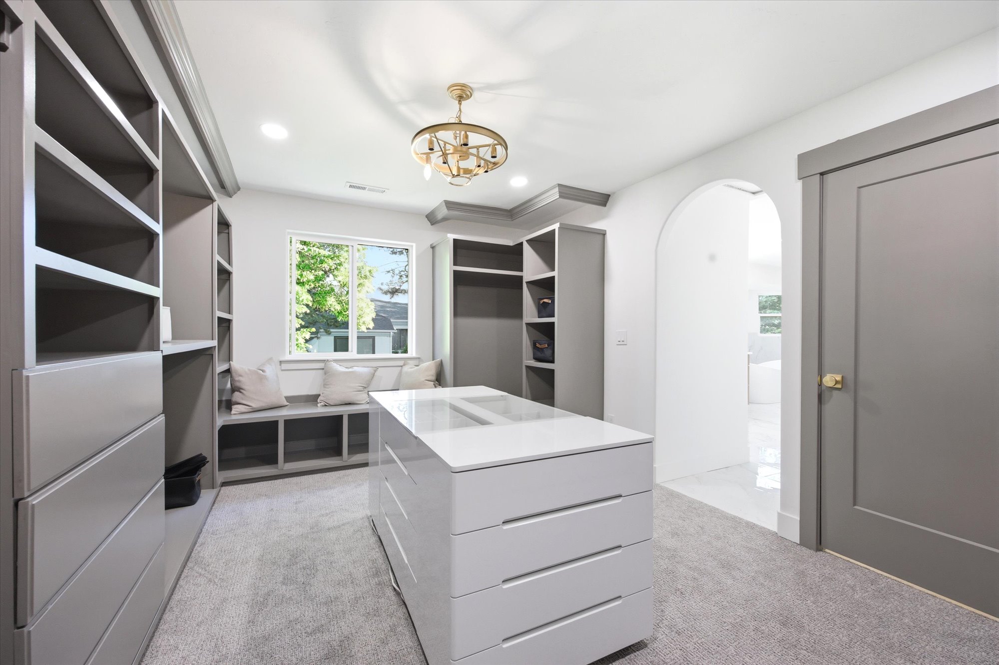 Custom closet system featuring a central island with a high-gloss finish, built-in shelving, and drawers