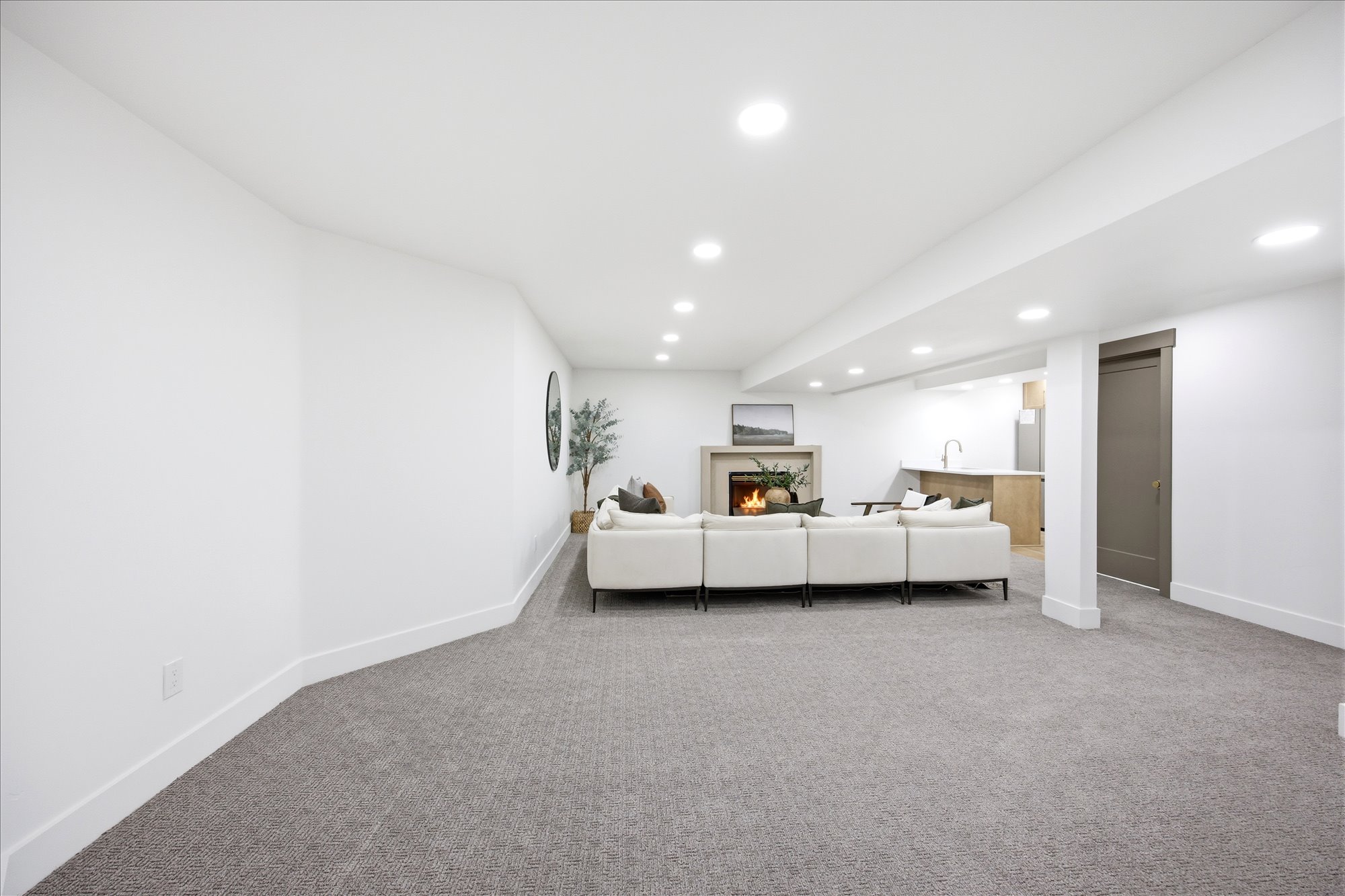 Spacious recreational room with gray patterned carpet flooring and recessed lighting