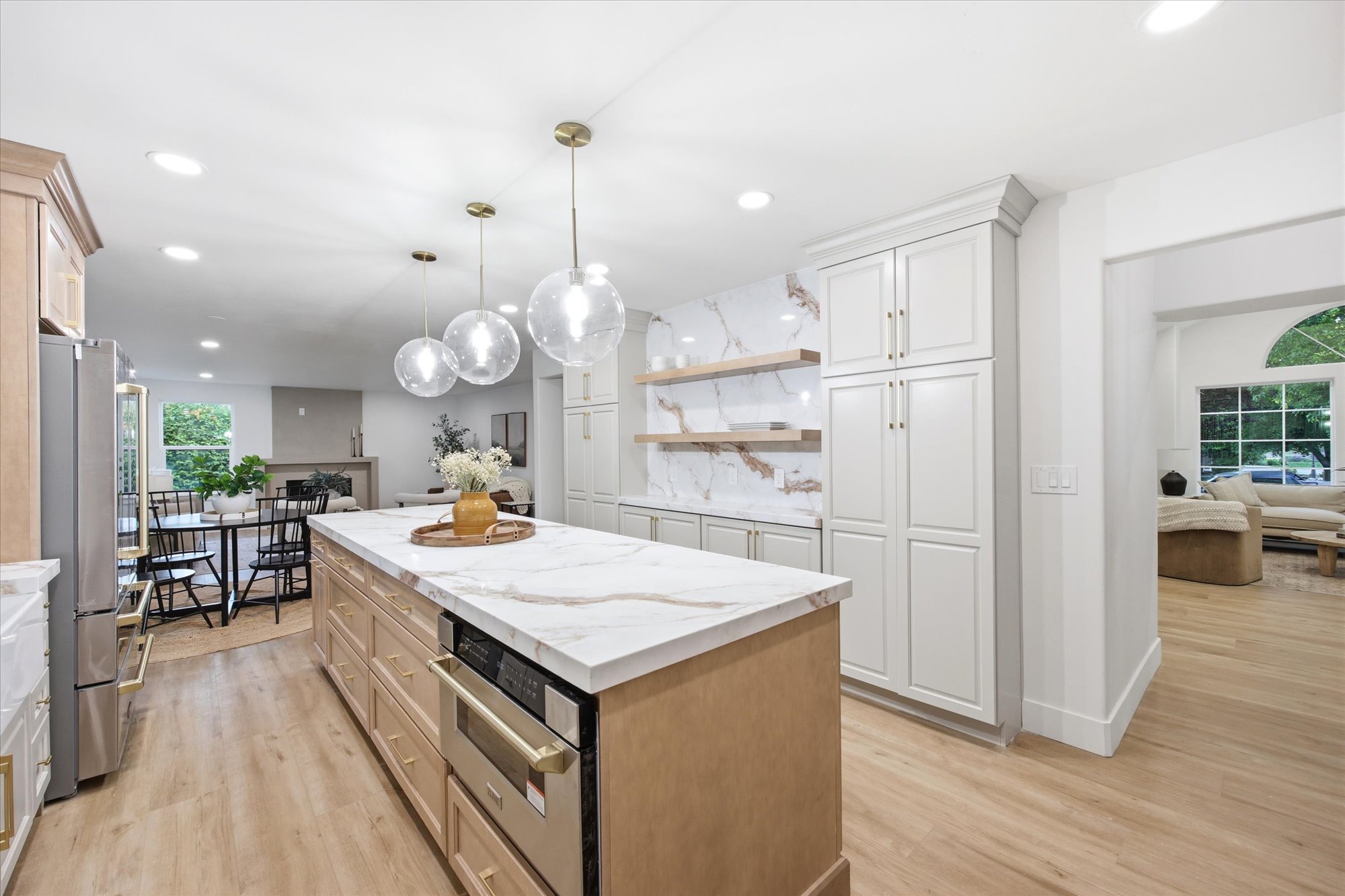 Kitchen featuring a large central island with a light-toned countertop, a built-in microwave, and wood-finish cabinetry
