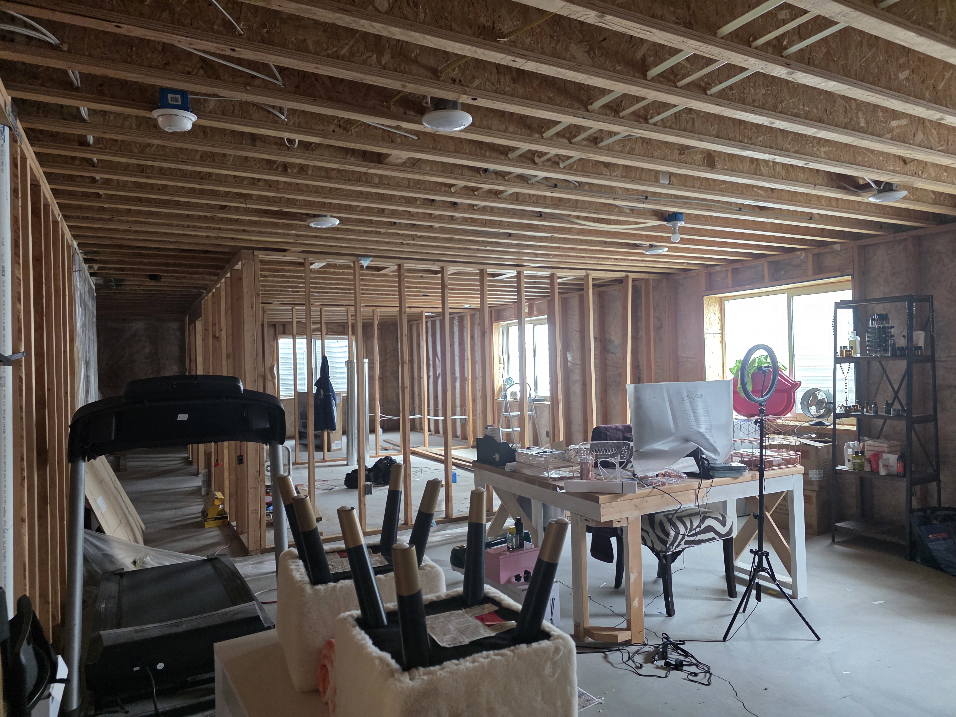Unfinished basement space featuring visible wood framing, exposed ceiling joists, multiple windows, and a concrete floor