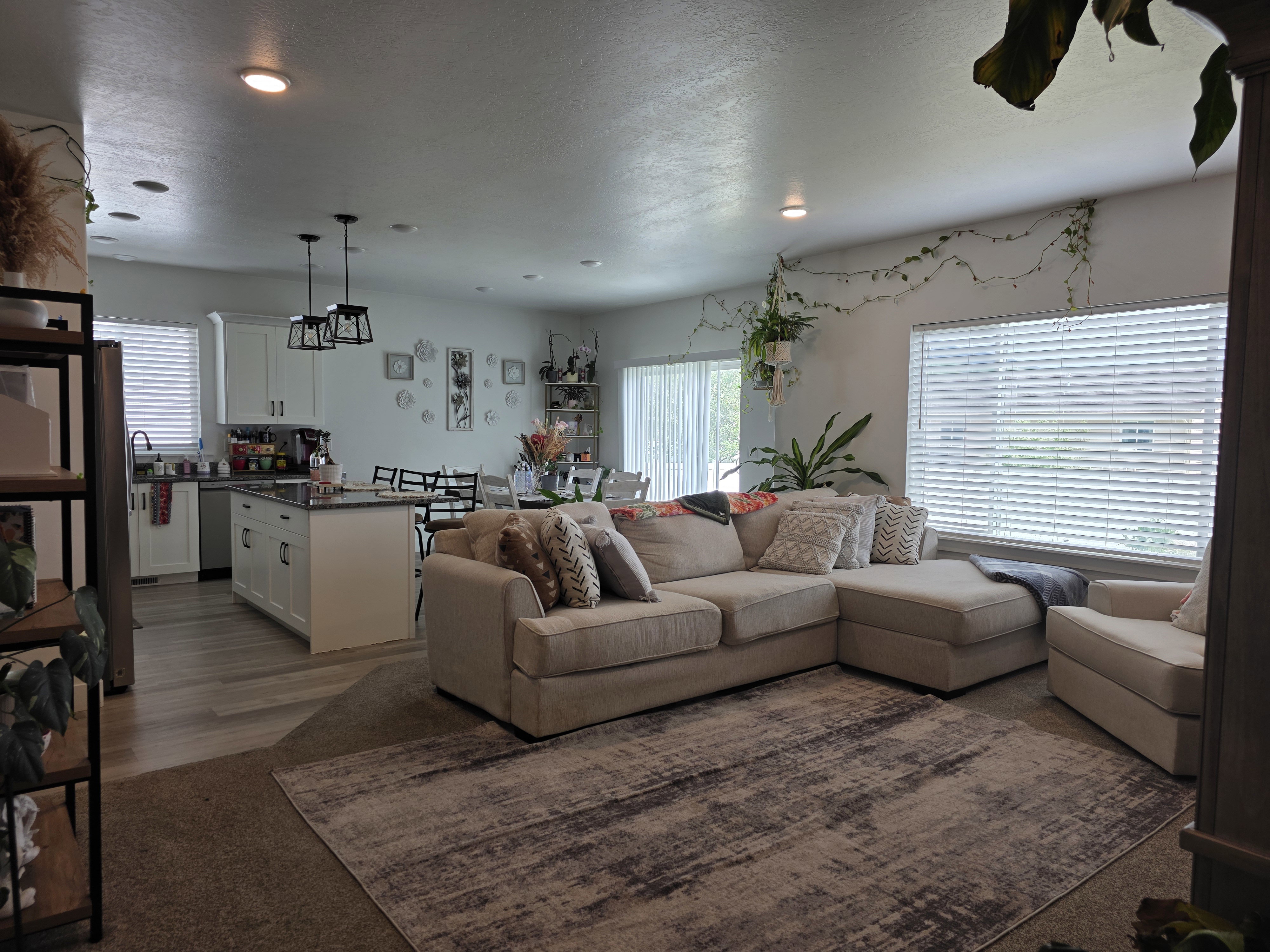 Open-concept living space featuring recessed lighting, large windows with horizontal blinds, and wood-finish flooring