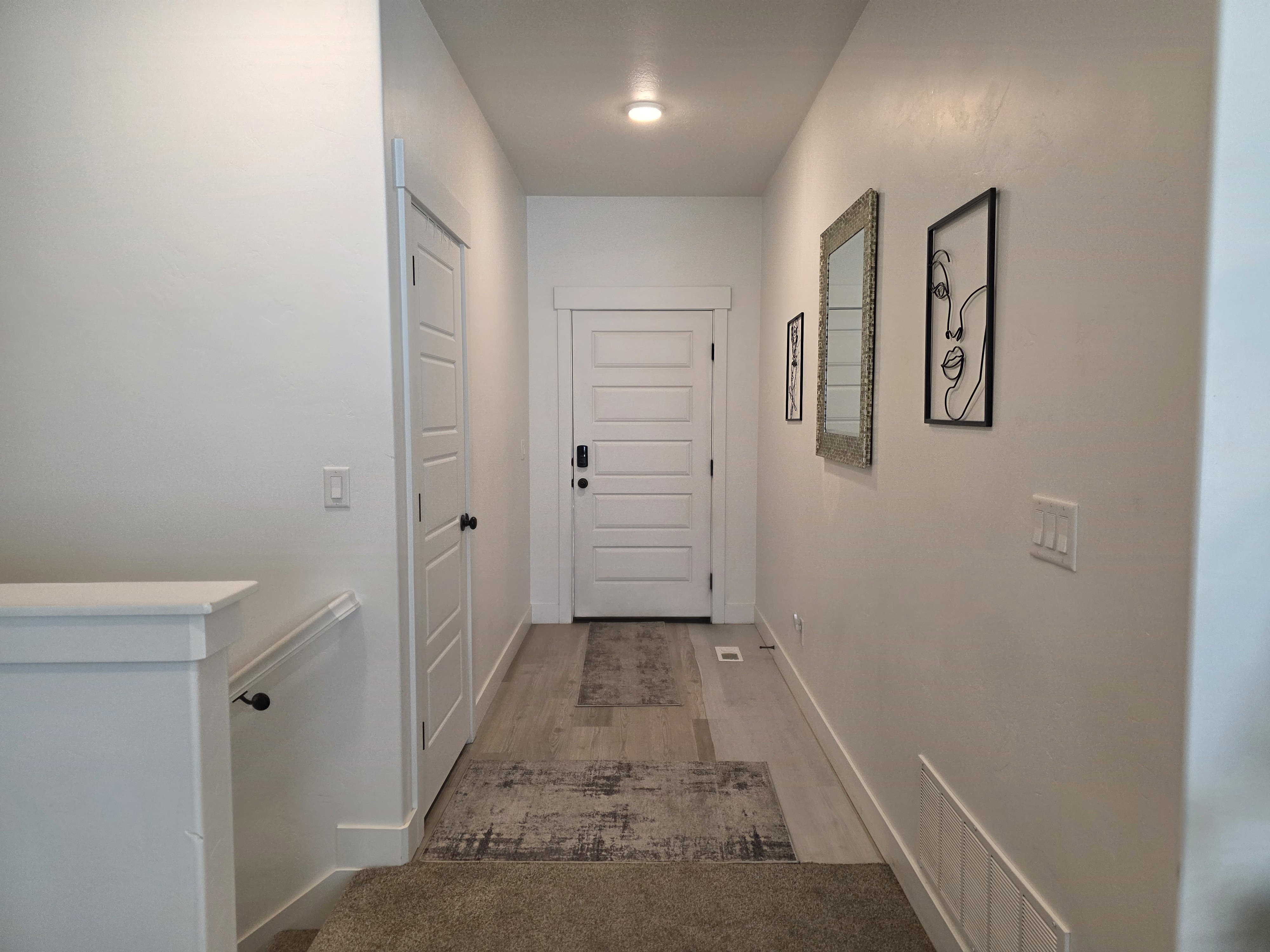 Hallway featuring recessed lighting, wood-finish flooring, a contemporary five-panel interior door, and white baseboards