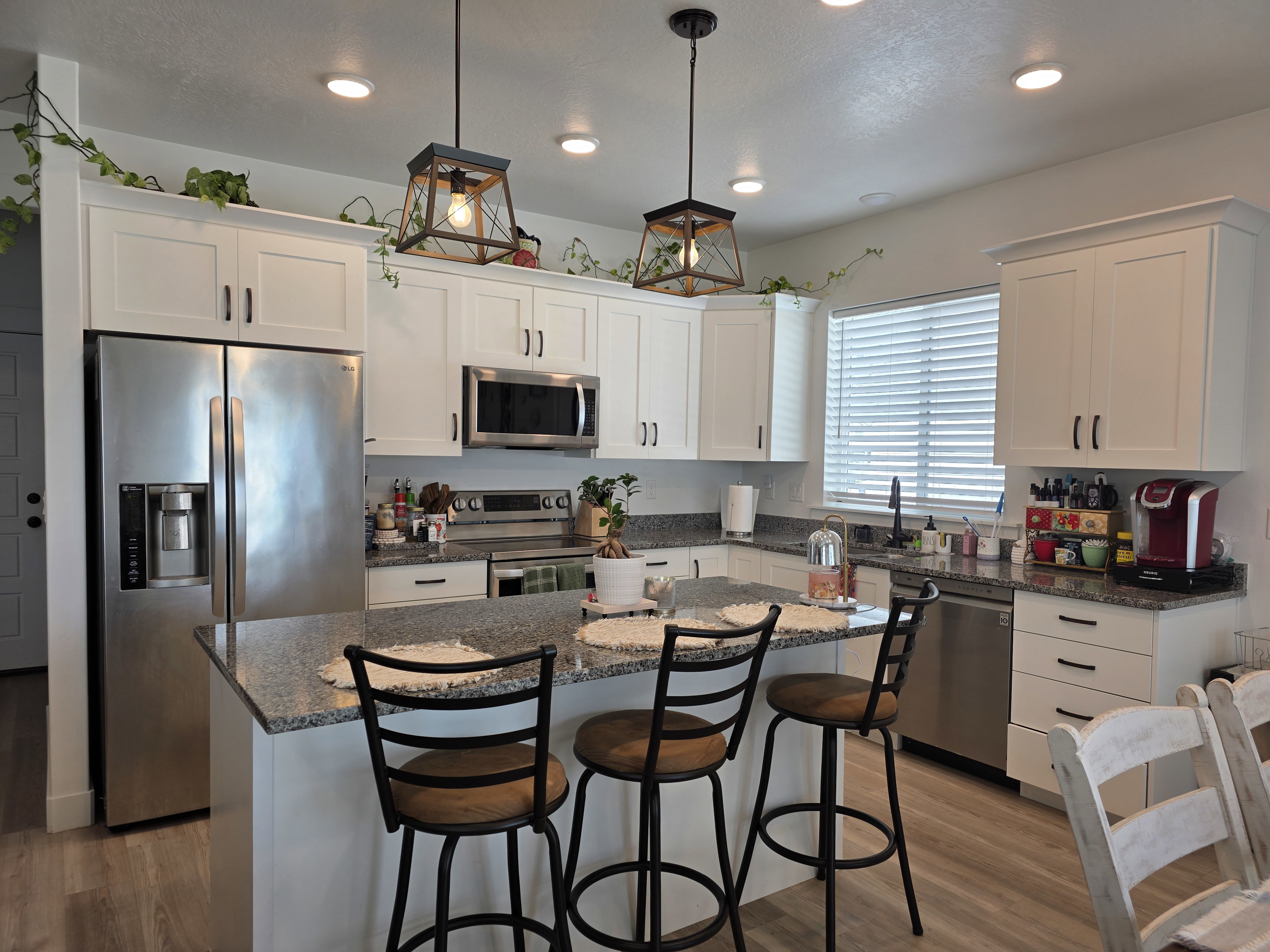 Kitchen featuring white cabinetry, stainless steel appliances, granite countertops, and light wood-finish flooring