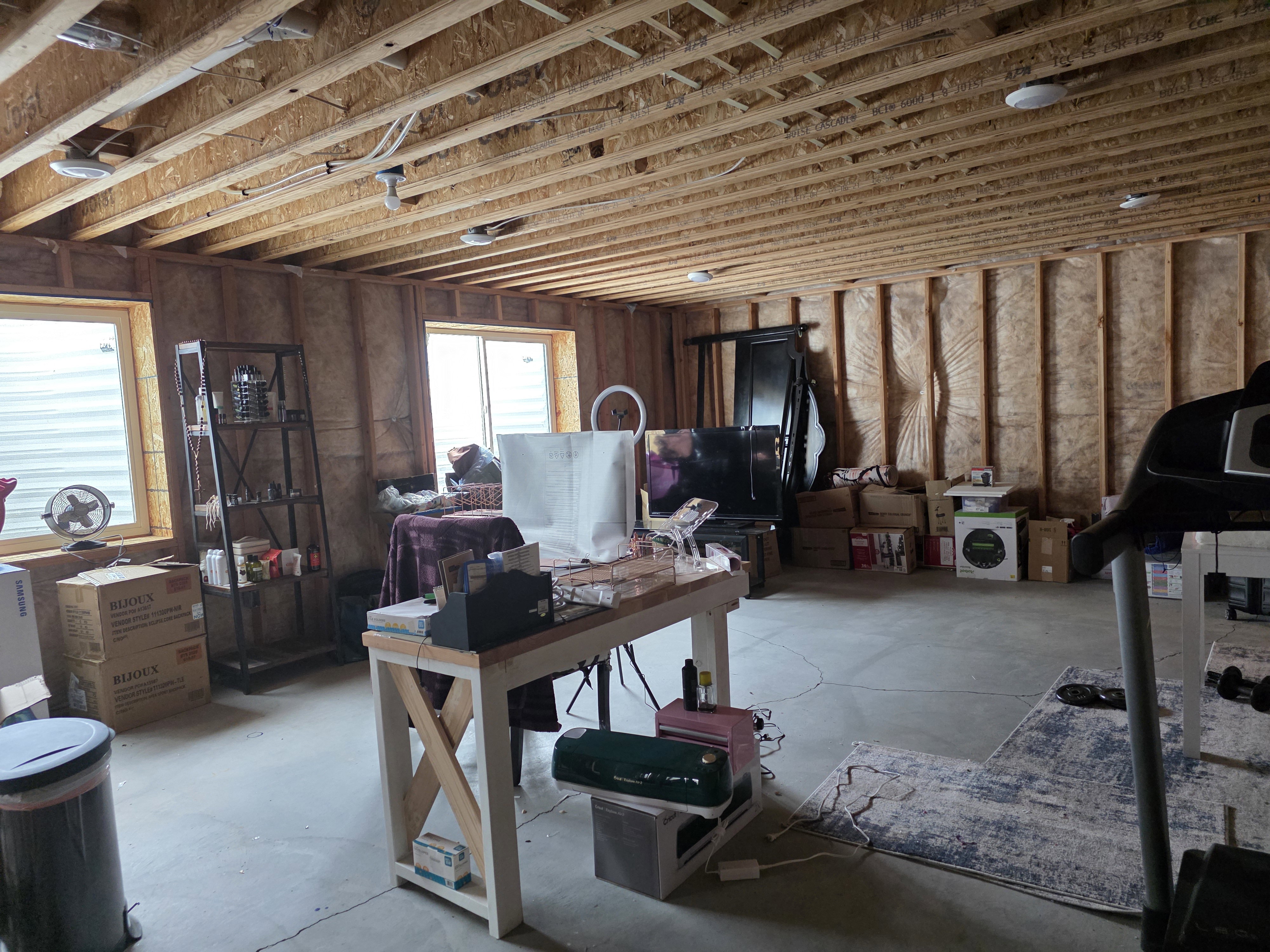 Unfinished basement space featuring exposed wood framing, concrete flooring, and multiple windows providing natural light