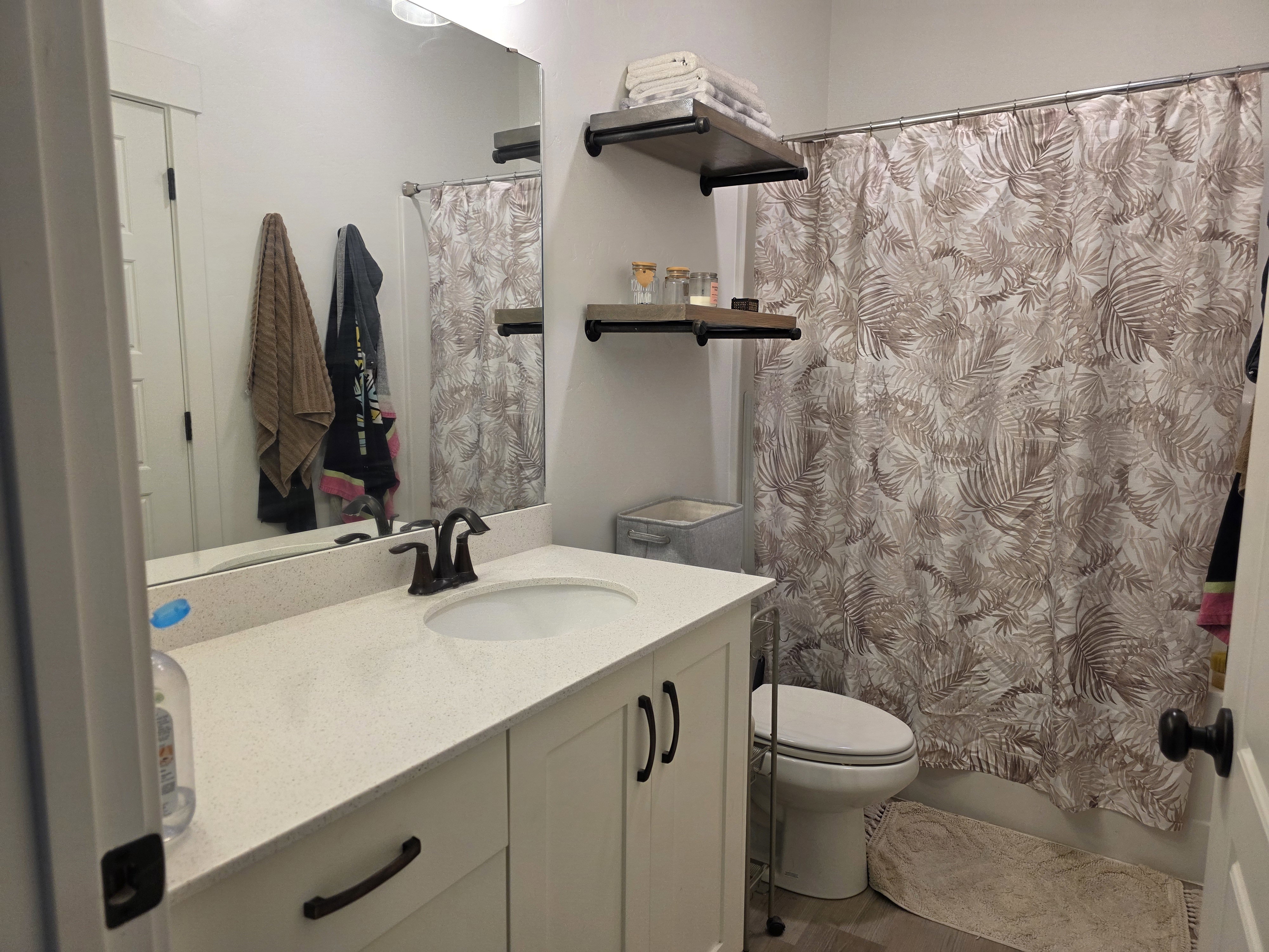 Bathroom featuring a white vanity with integrated sink, bronze-finish faucet, and a large wall-mounted mirror