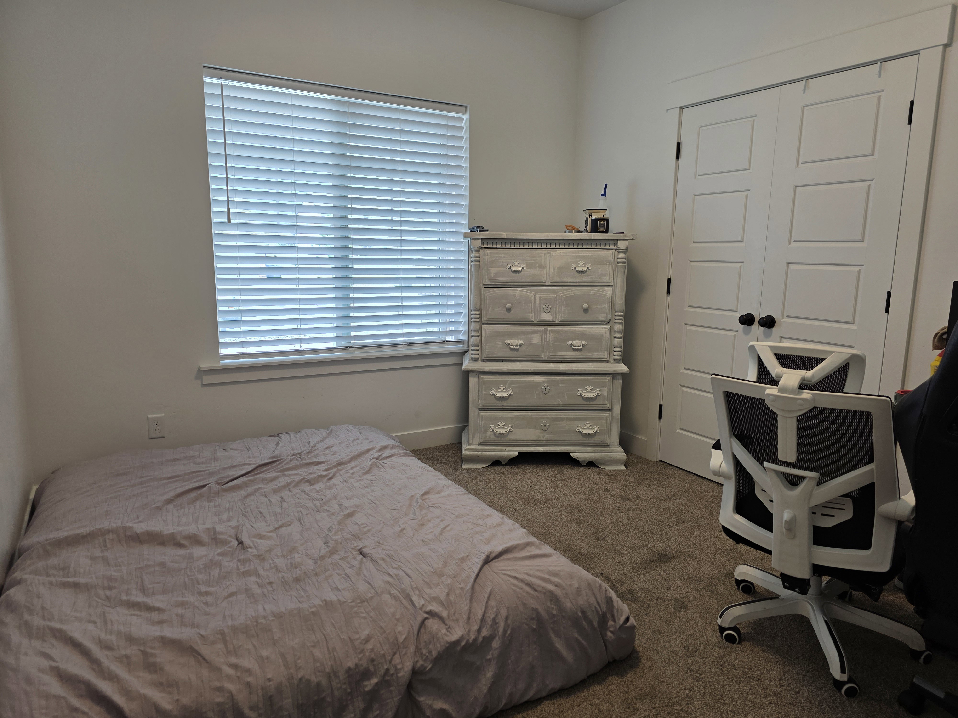 Room featuring neutral-toned carpeting, a window with horizontal blinds, and a white trim package