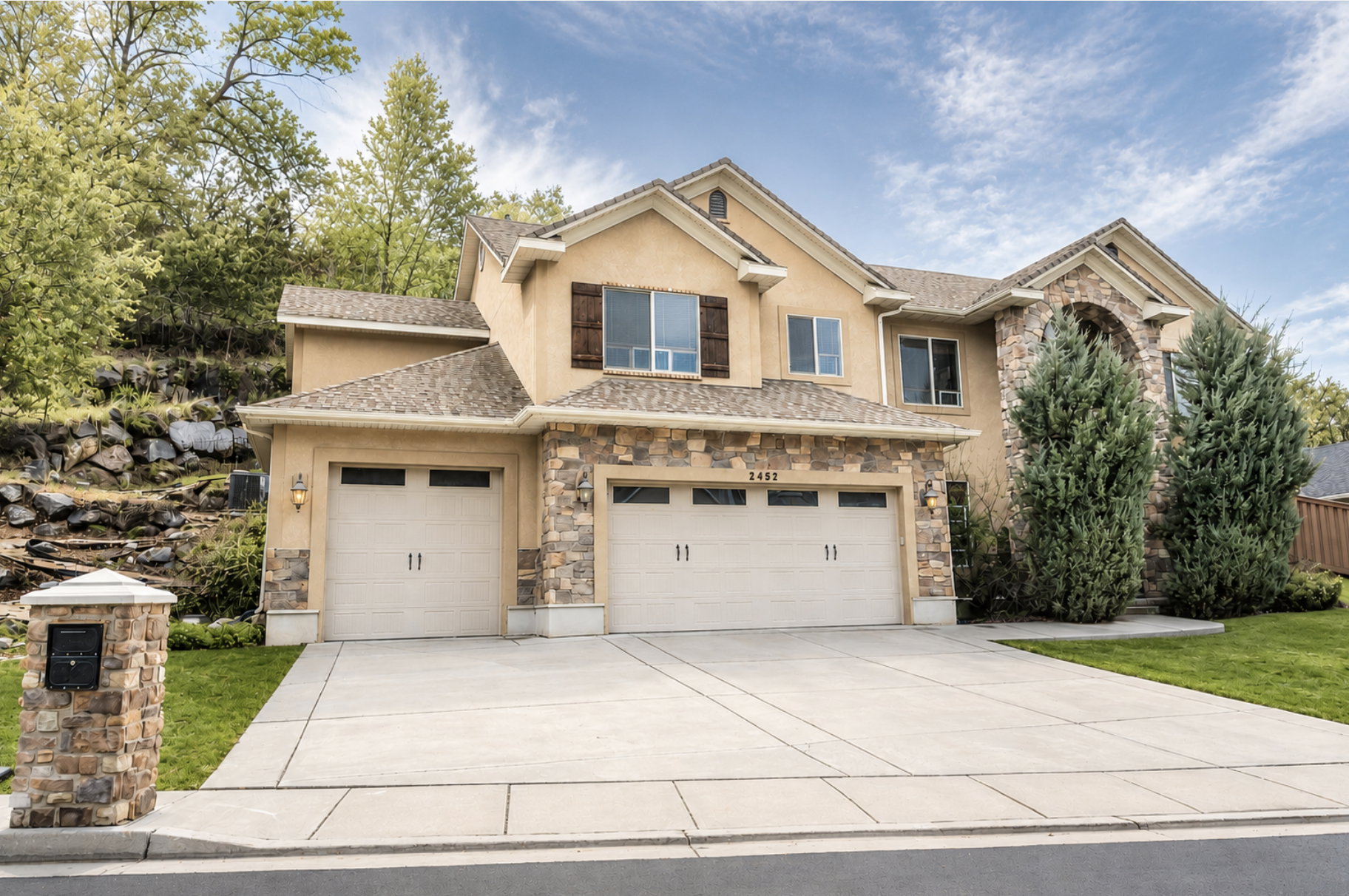 Stucco and stone exterior featuring multiple gables and a prominent arched entry