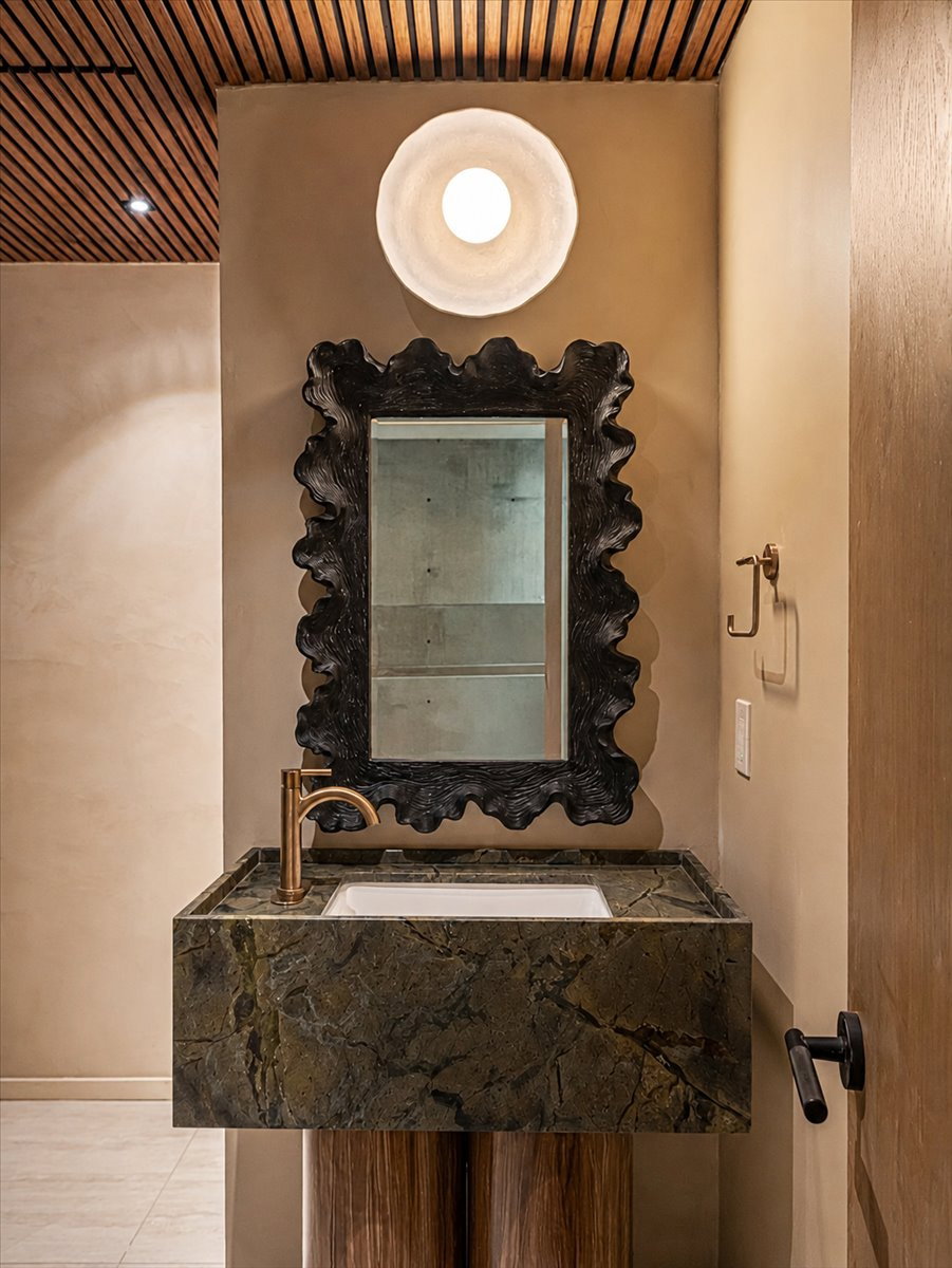 Powder room featuring a sculptural wood-finish ceiling, a floating vanity with an integrated stone sink, a unique organic-form mirror, and a modern wall sconce