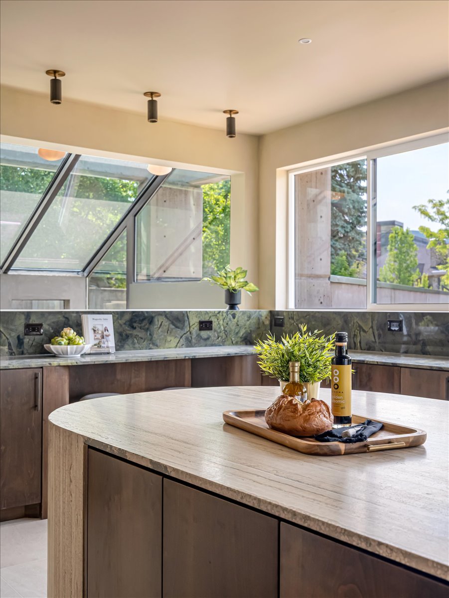 Kitchen featuring a curved central island with a light-toned countertop, dark wood-finish cabinetry, and green patterned stone countertops