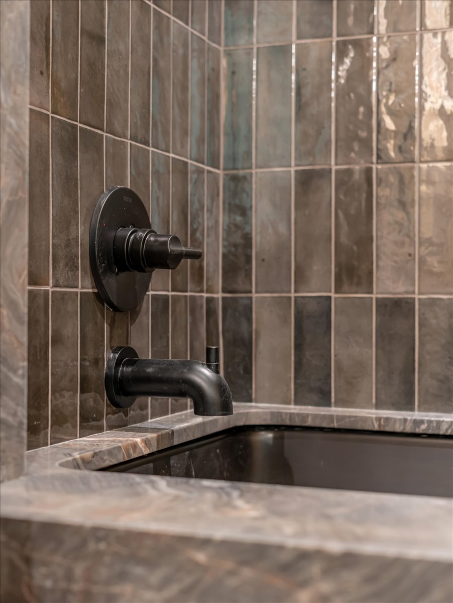 Integrated bathtub with a surround and matte black fixtures, complemented by vertical tile wall detailing