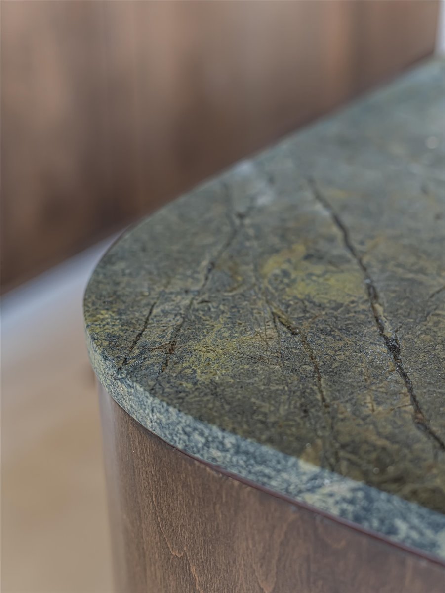 Stone countertop with natural veining and a rounded edge, paired with curved wood-finish cabinetry