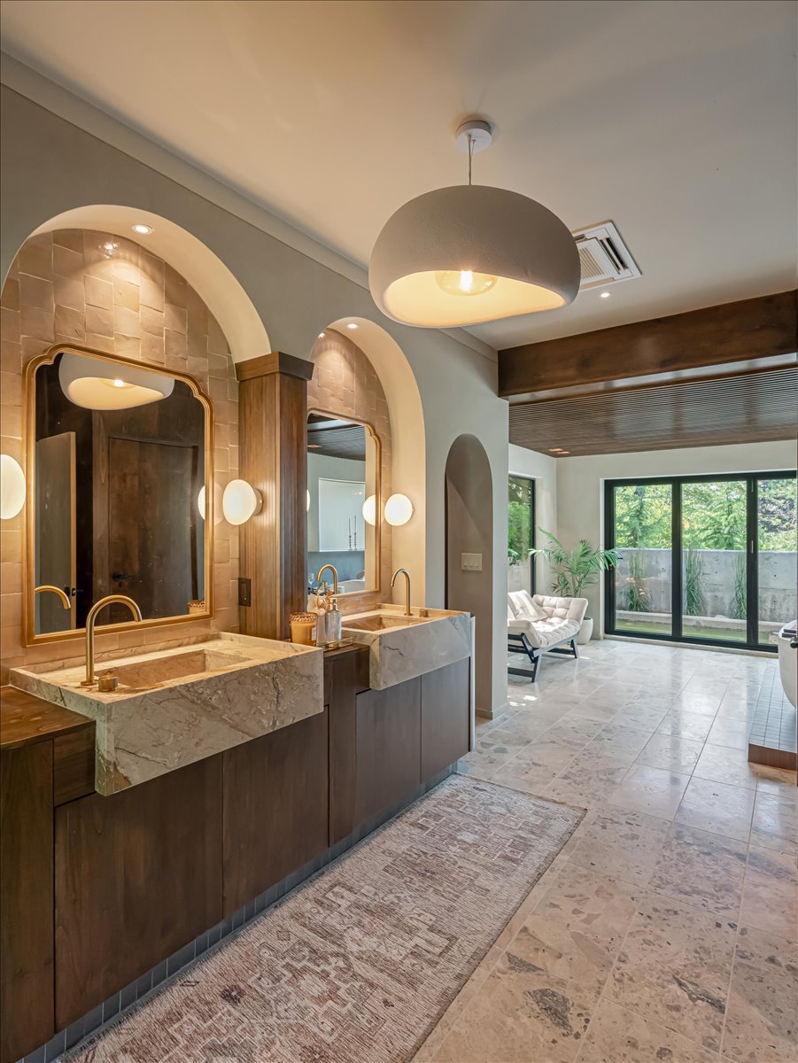Dual stone vessel sinks with brass fixtures set into a wood-finish vanity