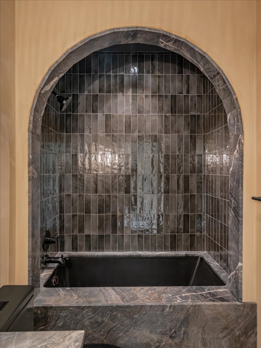 Arched alcove featuring a dark soaking tub