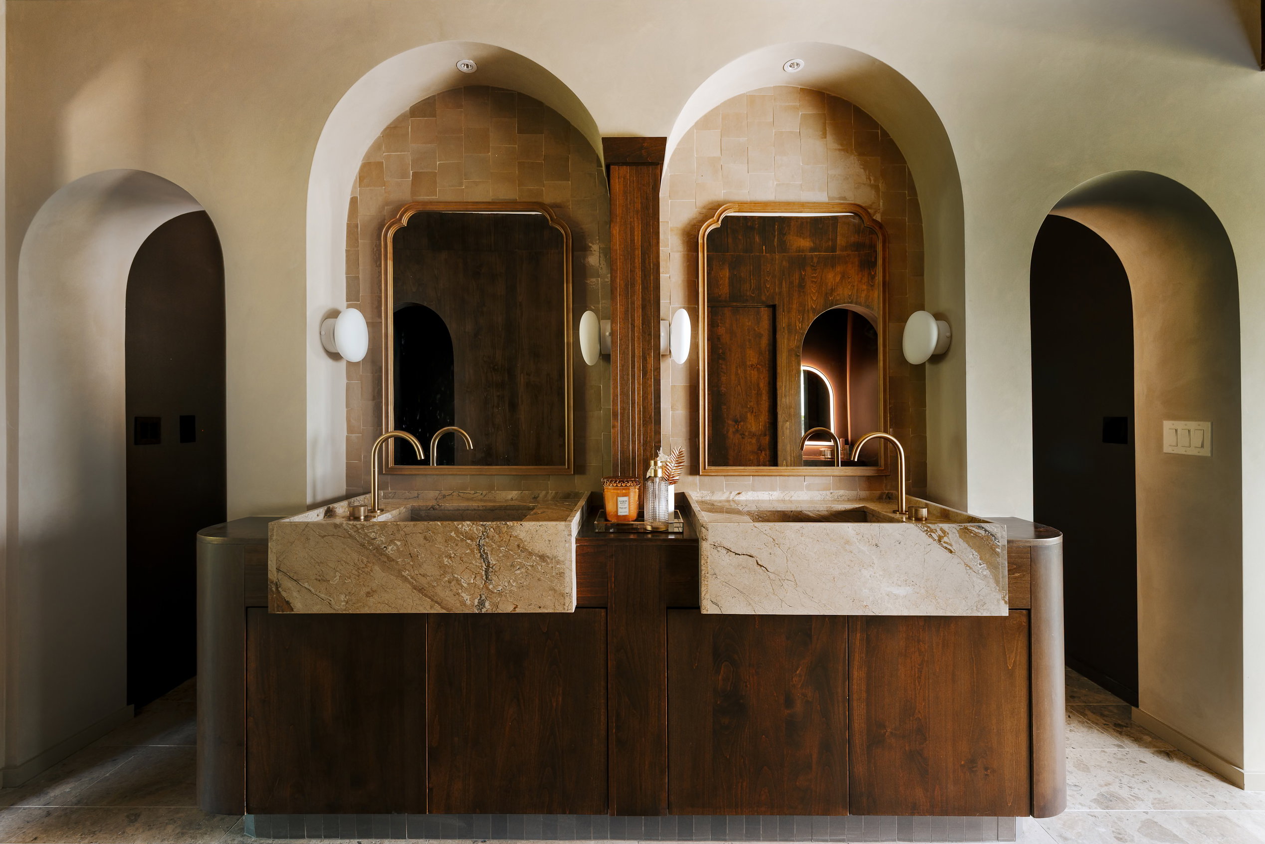 Dual arched vanity with integrated natural stone sinks and wood-finish cabinetry