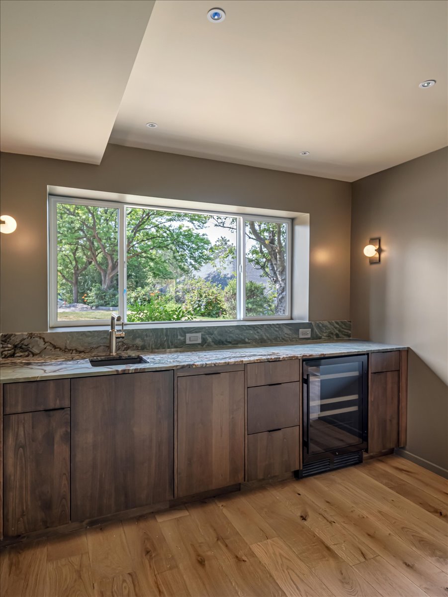 Featuring a contemporary sink, sleek faucet, under-counter beverage refrigerator, and wood-finish cabinetry