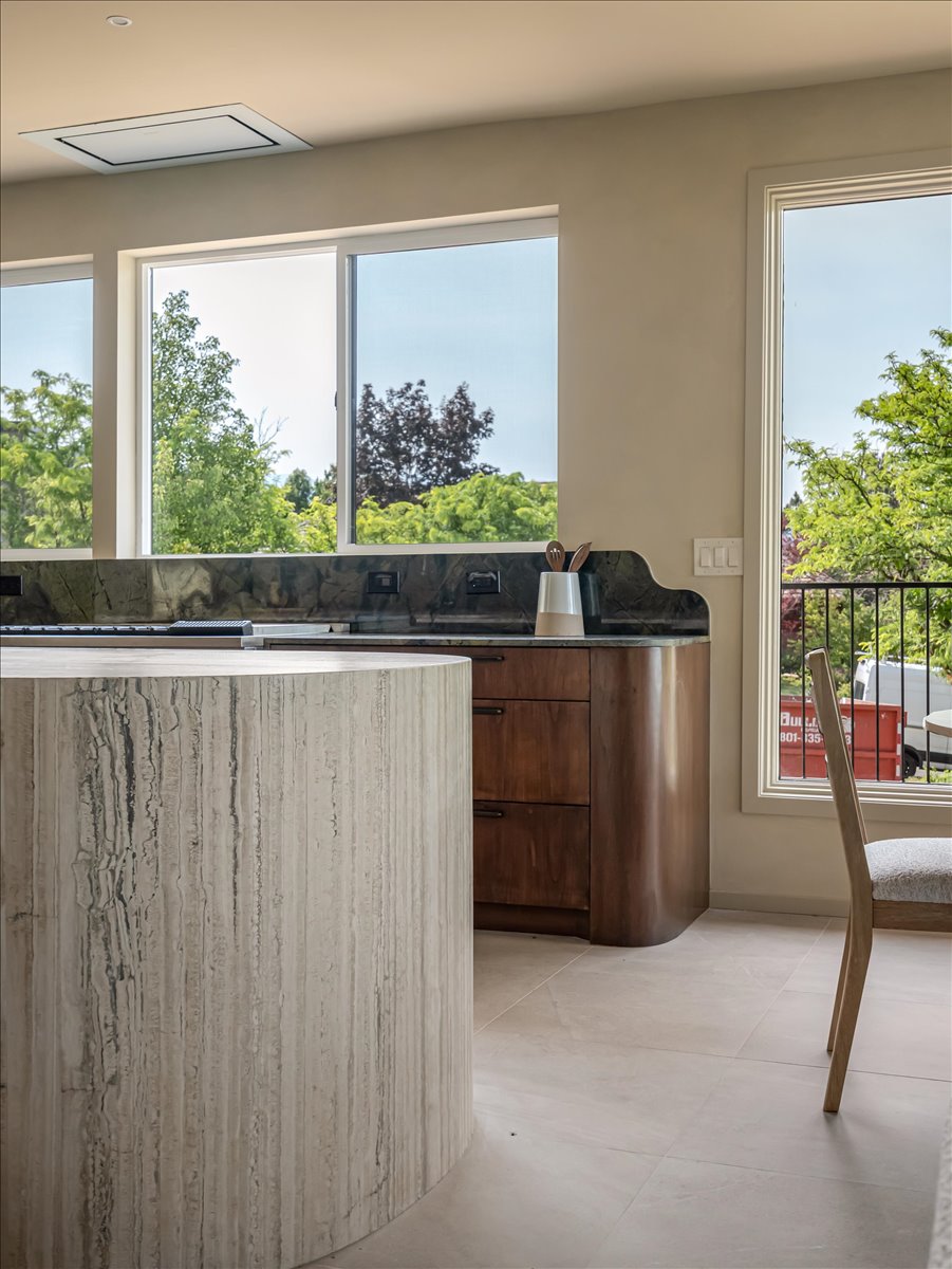 Curved stone-look island with integrated countertop, complemented by dark wood cabinetry