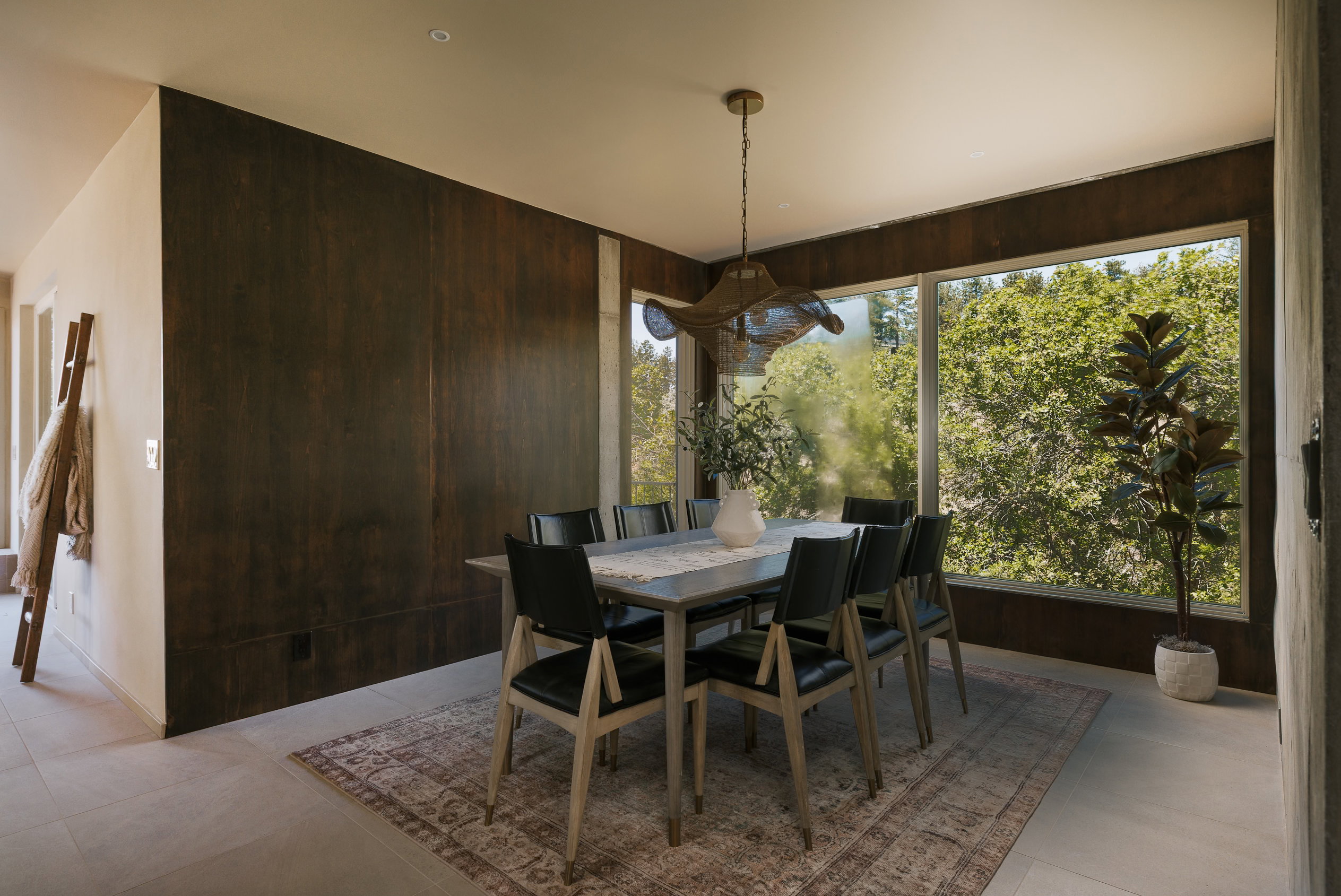 Dining area featuring expansive windows, wood-finish wall panels, recessed lighting, and light-toned tile flooring