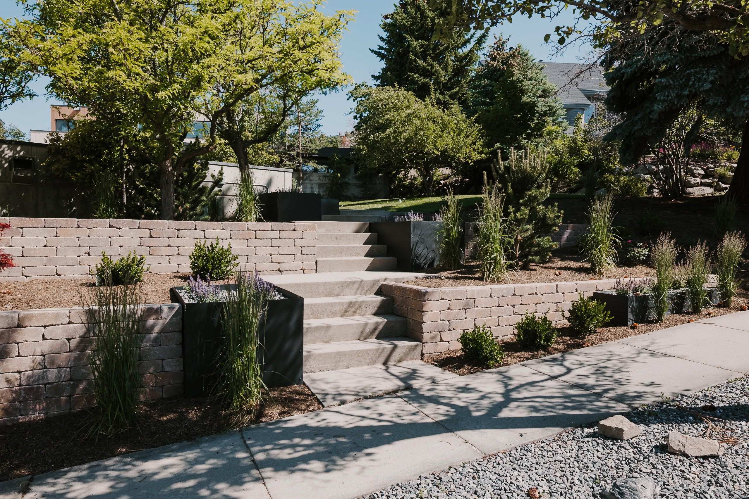 Tiered landscaping featuring retaining walls, integrated planters, and mature trees