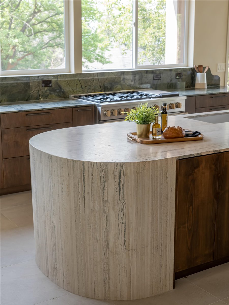 Kitchen island featuring a rounded, light-toned stone base with vertical veining and a smooth stone countertop