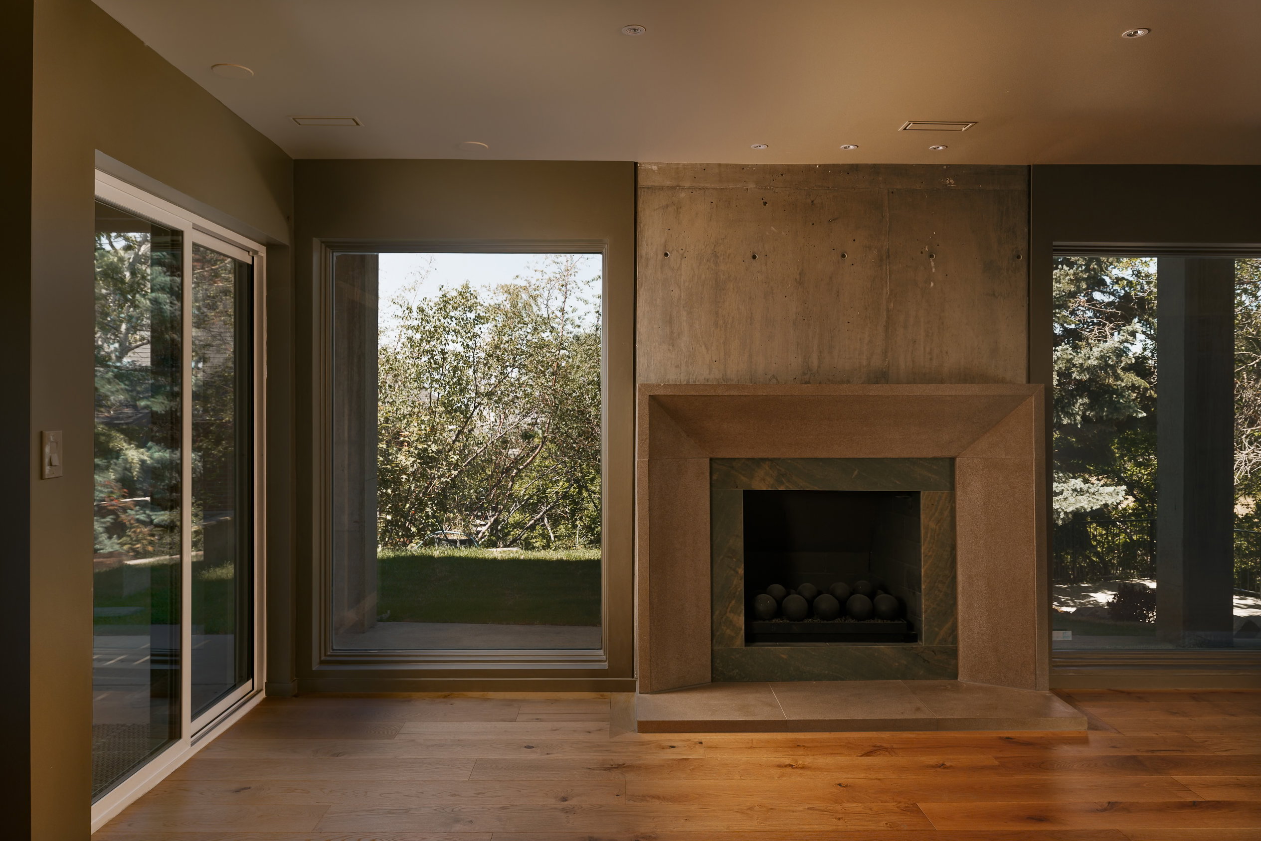 Spacious room featuring a contemporary fireplace with a stone surround, large sliding glass door, oversized window, recessed lighting, and flooring