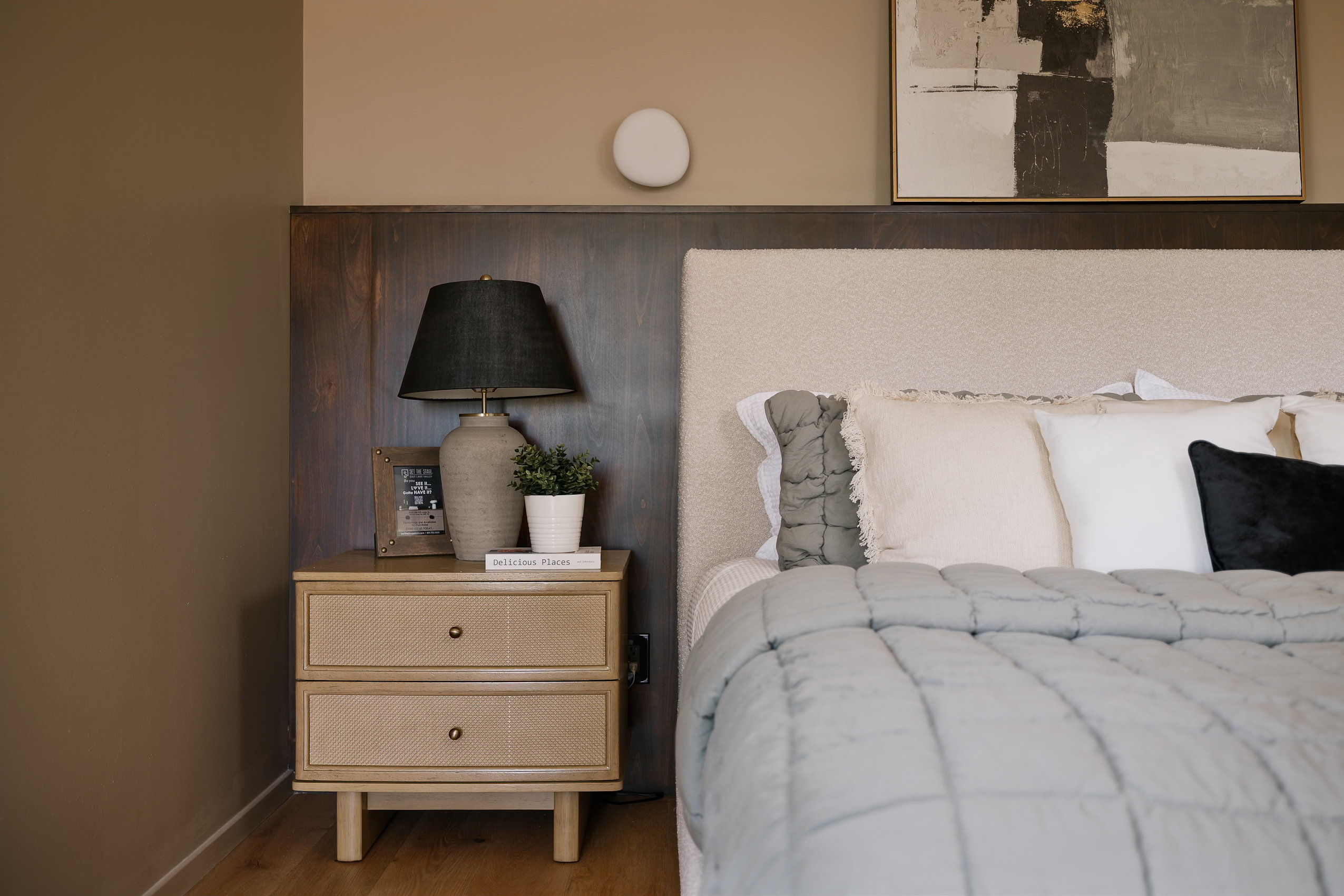 Upholstered headboard with dark wood paneling and a wall-mounted sconce