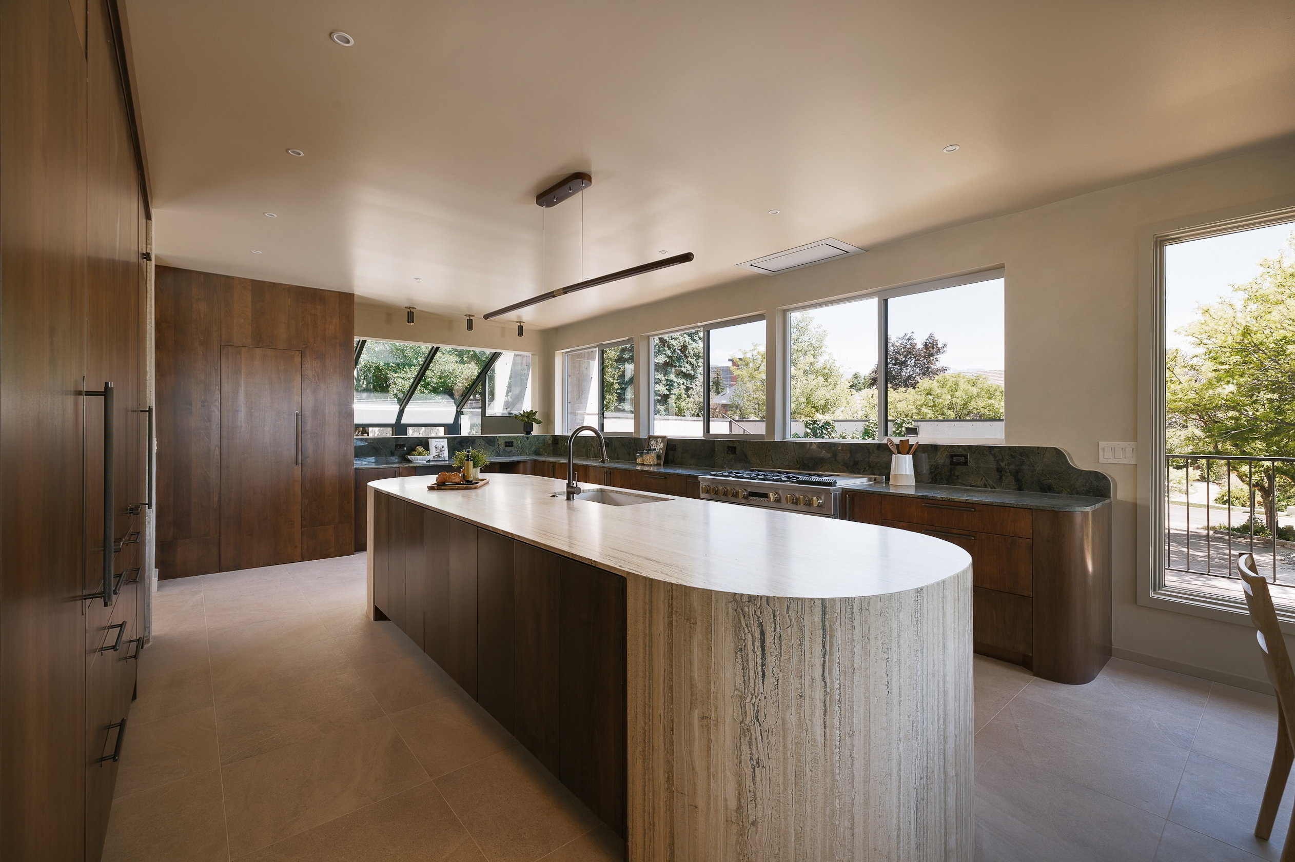 Modern kitchen featuring a large curved island with a light stone finish countertop