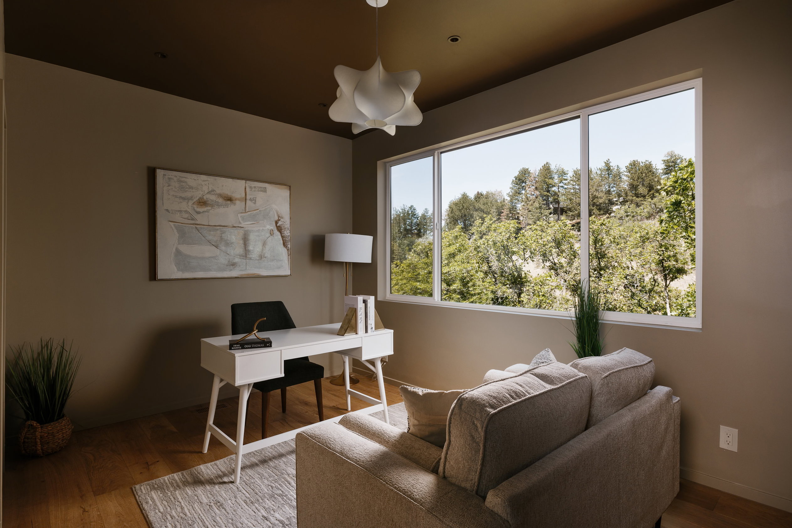 Spacious room featuring wood-finish flooring, a large multi-pane window, and a contemporary ceiling light fixture