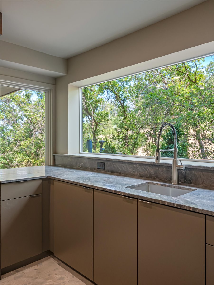 Kitchen featuring expansive casement windows, stone countertops, undermount sink, gooseneck faucet, and flat-panel cabinetry
