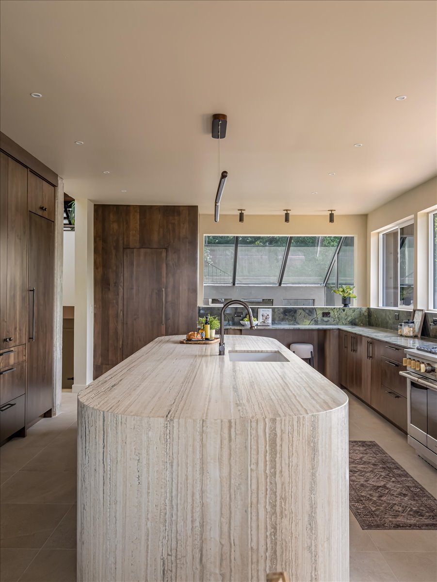 Kitchen island featuring a waterfall countertop with integrated sink\
