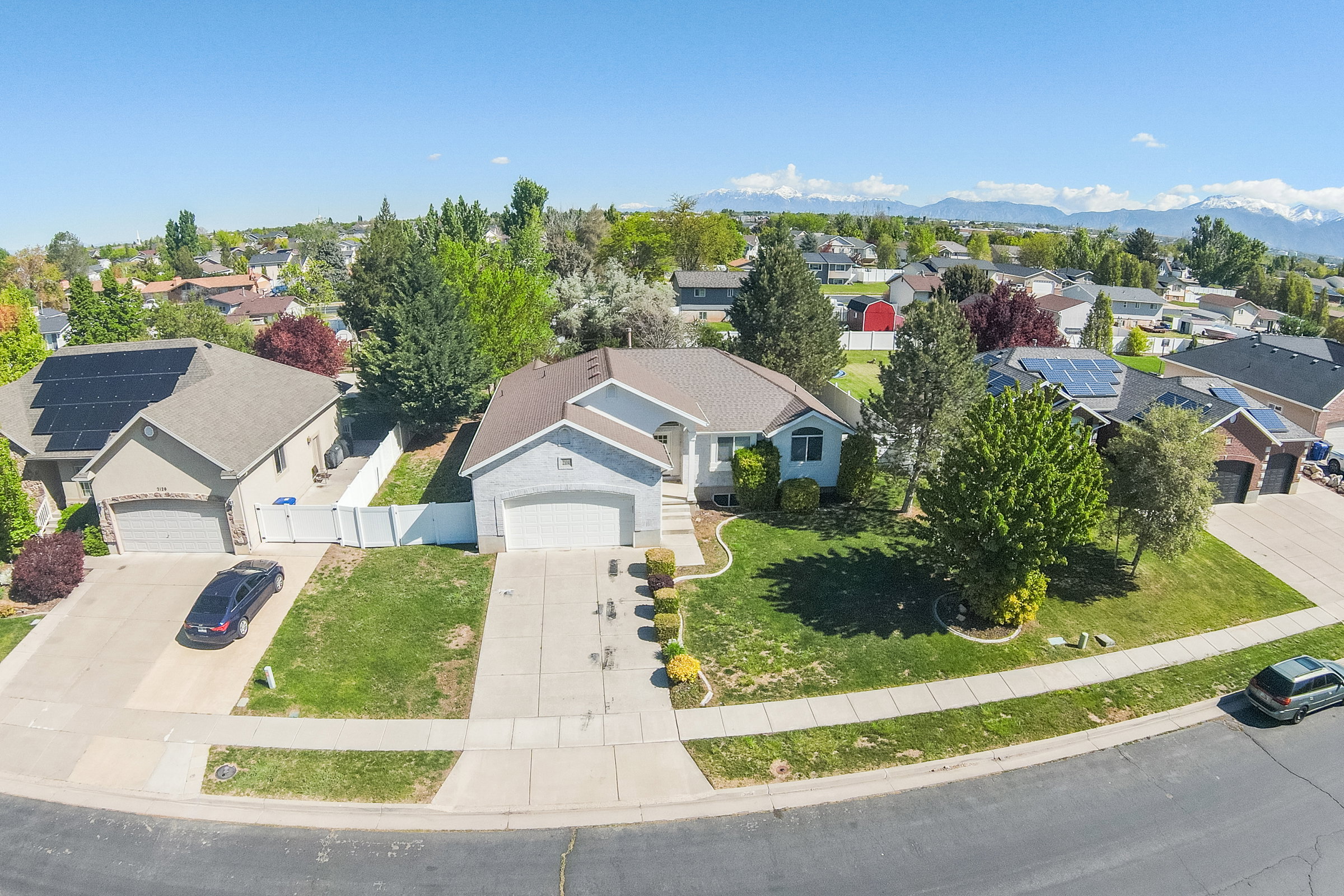 Suburban residence featuring a pitched roof, attached front-entry garage, mature landscaping, and a paved driveway