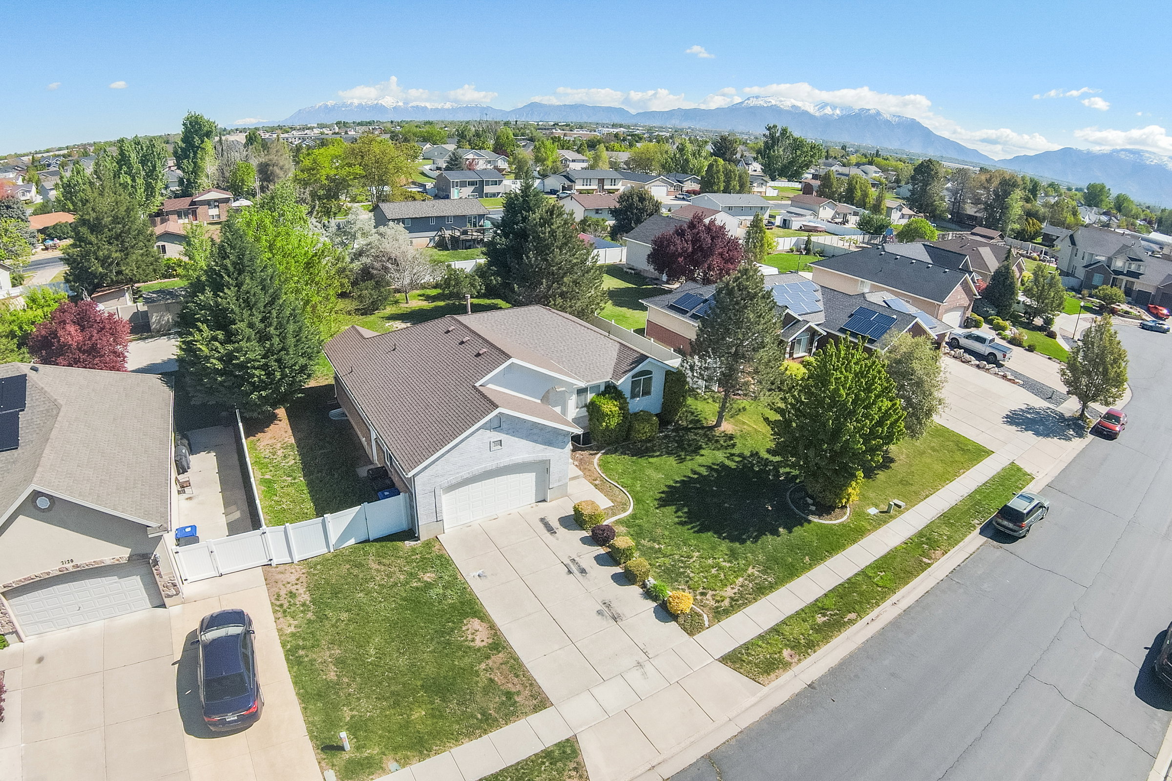 Aerial perspective showcasing a residential property with a partial two-story design, an attached two-car garage, and a brown shingle roof