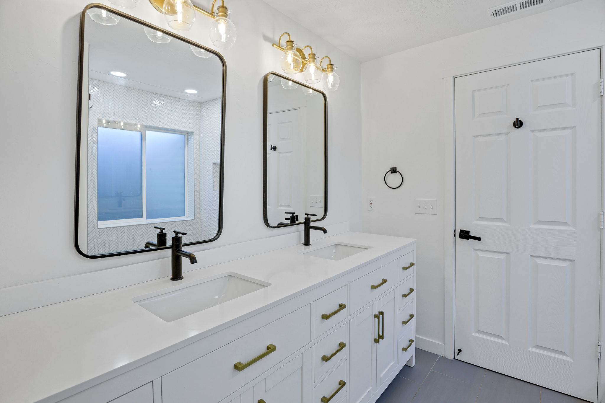 Dual vanity featuring white cabinetry, integrated sinks, white countertops, and matte black fixtures