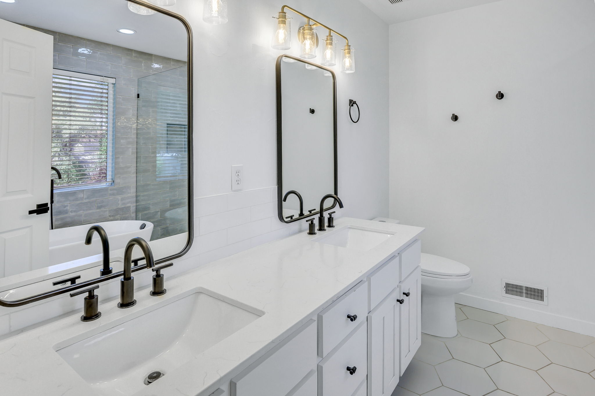 Dual vanity with white cabinetry and integrated sinks, accented by black hardware and fixtures