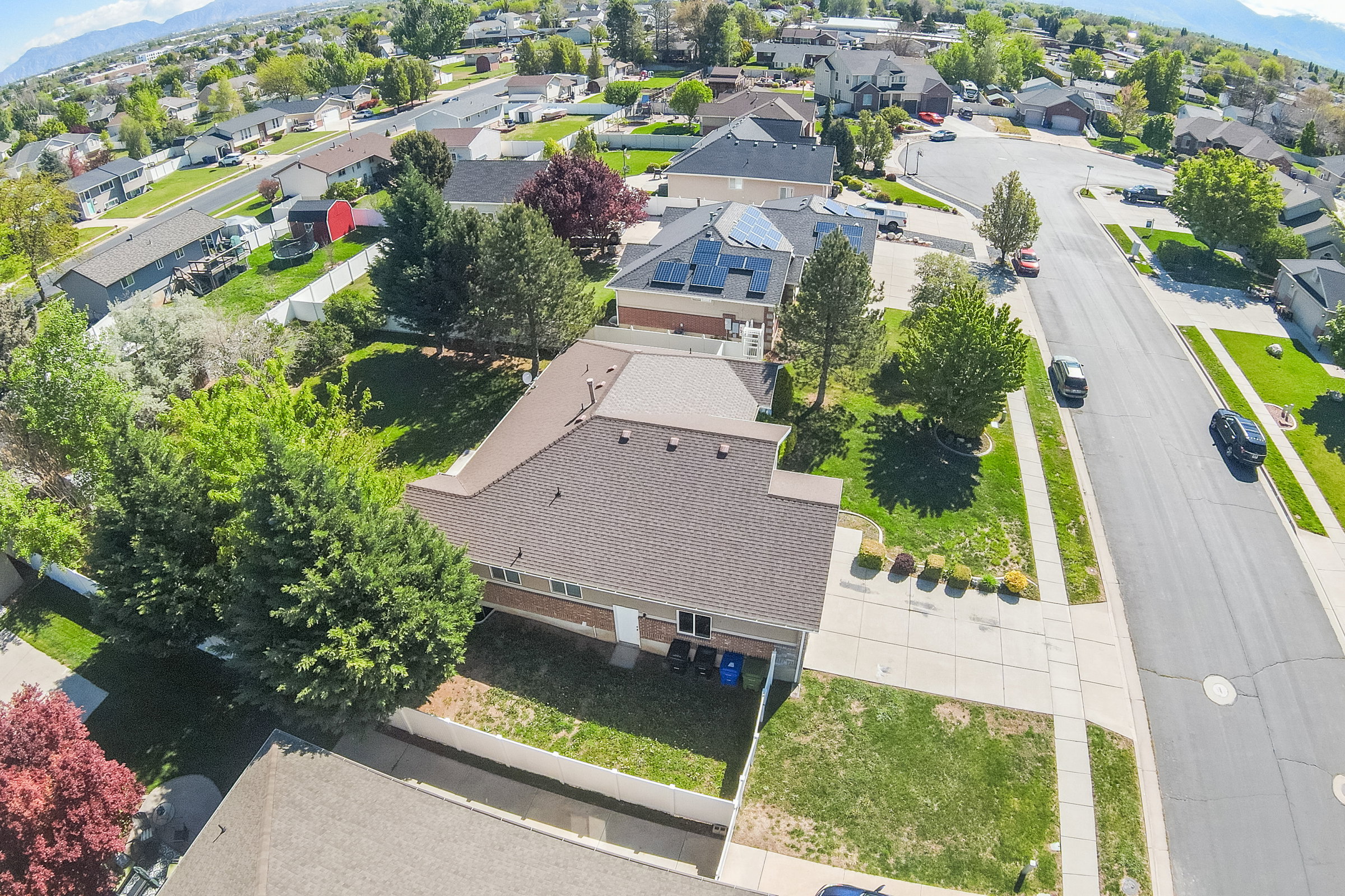 Aerial perspective of a suburban neighborhood featuring residential homes with shingle roofs and established landscaping