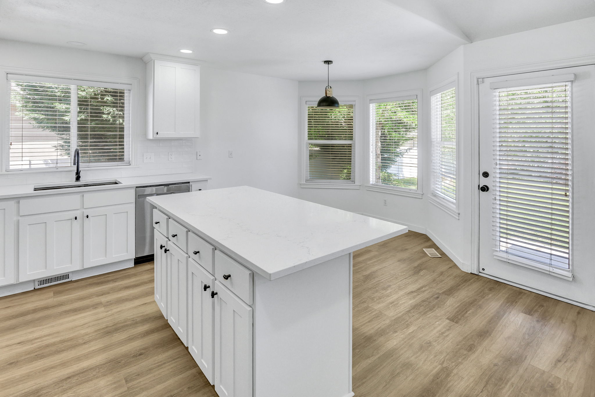 Modern kitchen featuring a central island with white cabinetry and a light-toned countertop