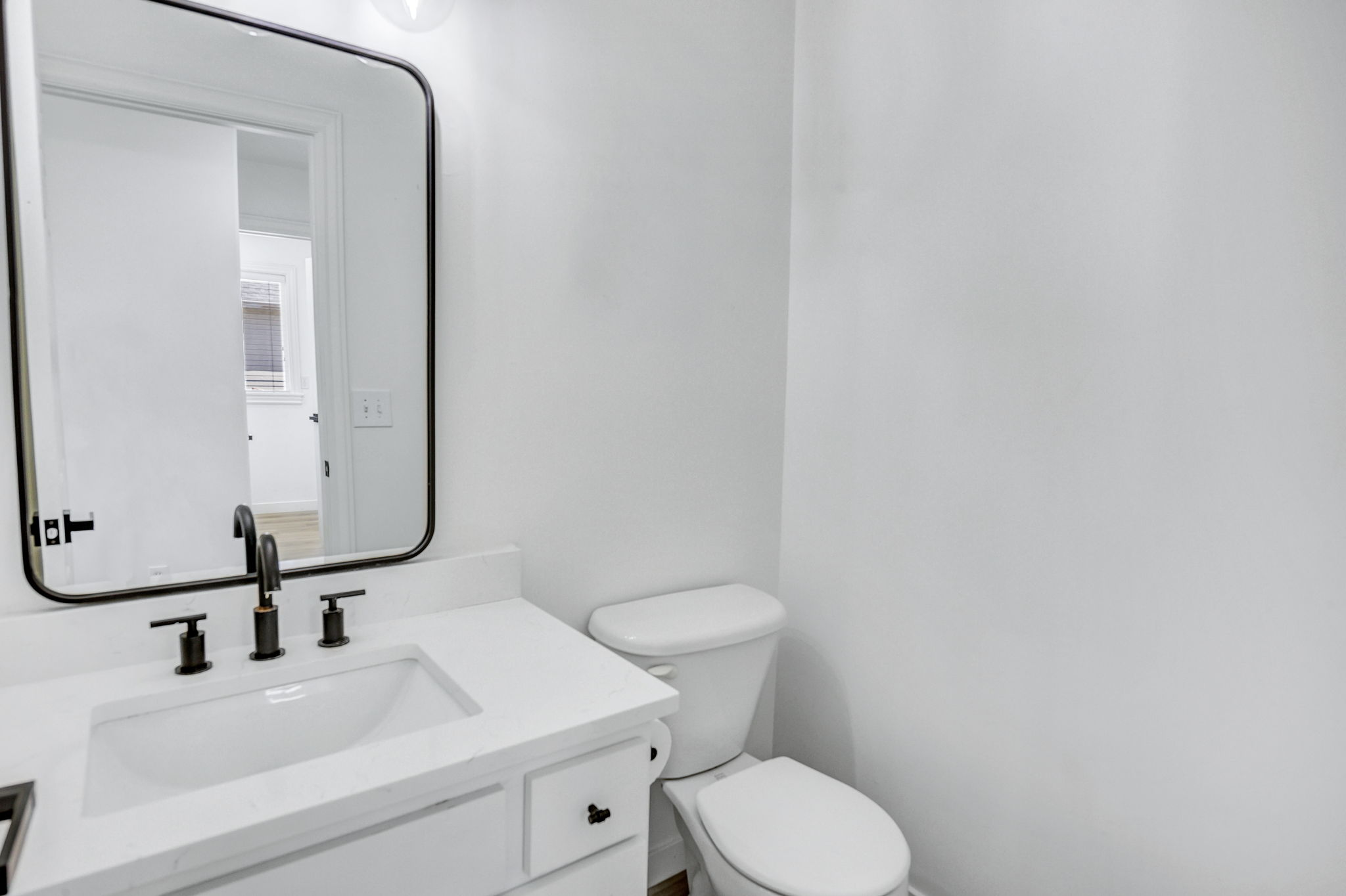 Bathroom vanity featuring a rectangular undermount sink, a white countertop, and a matte black faucet