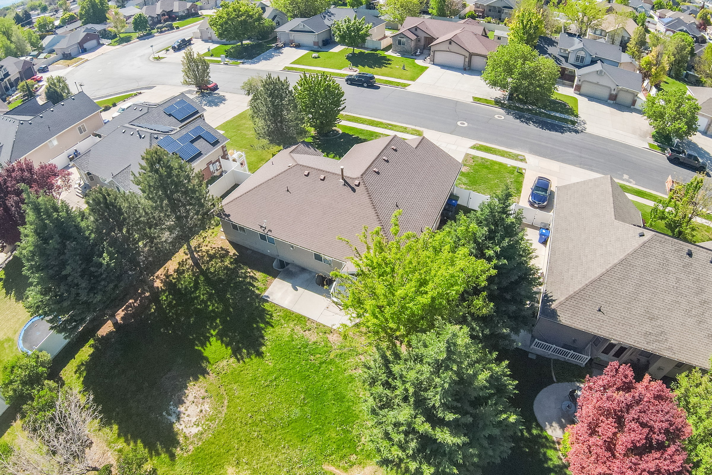 Aerial perspective showcasing a residential property with a brown shingle roof and light-colored siding