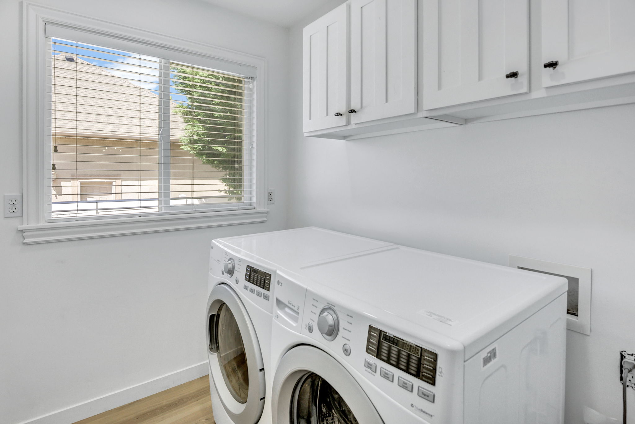 Laundry area featuring white shaker-style cabinetry with dark hardware