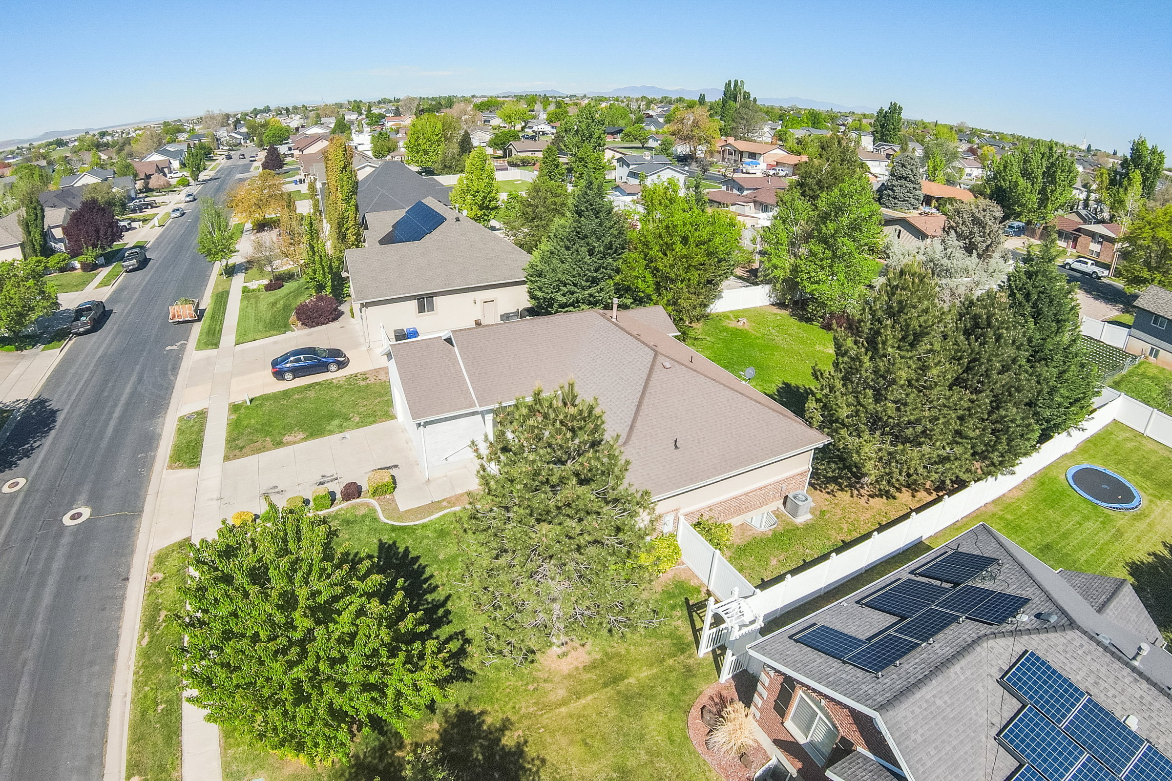 Residential street featuring a single-family home with a shingled roof, a paved driveway, and mature landscaping