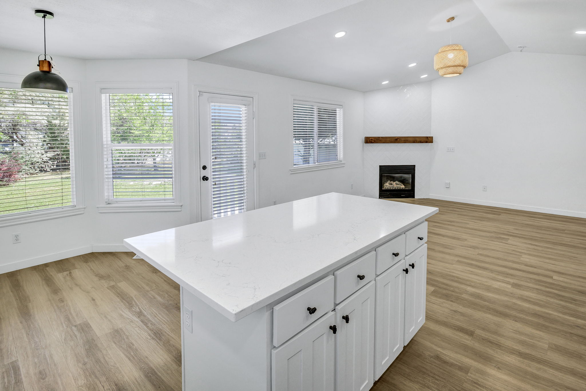 Kitchen island featuring a white countertop with integrated sink and white cabinetry with black hardware