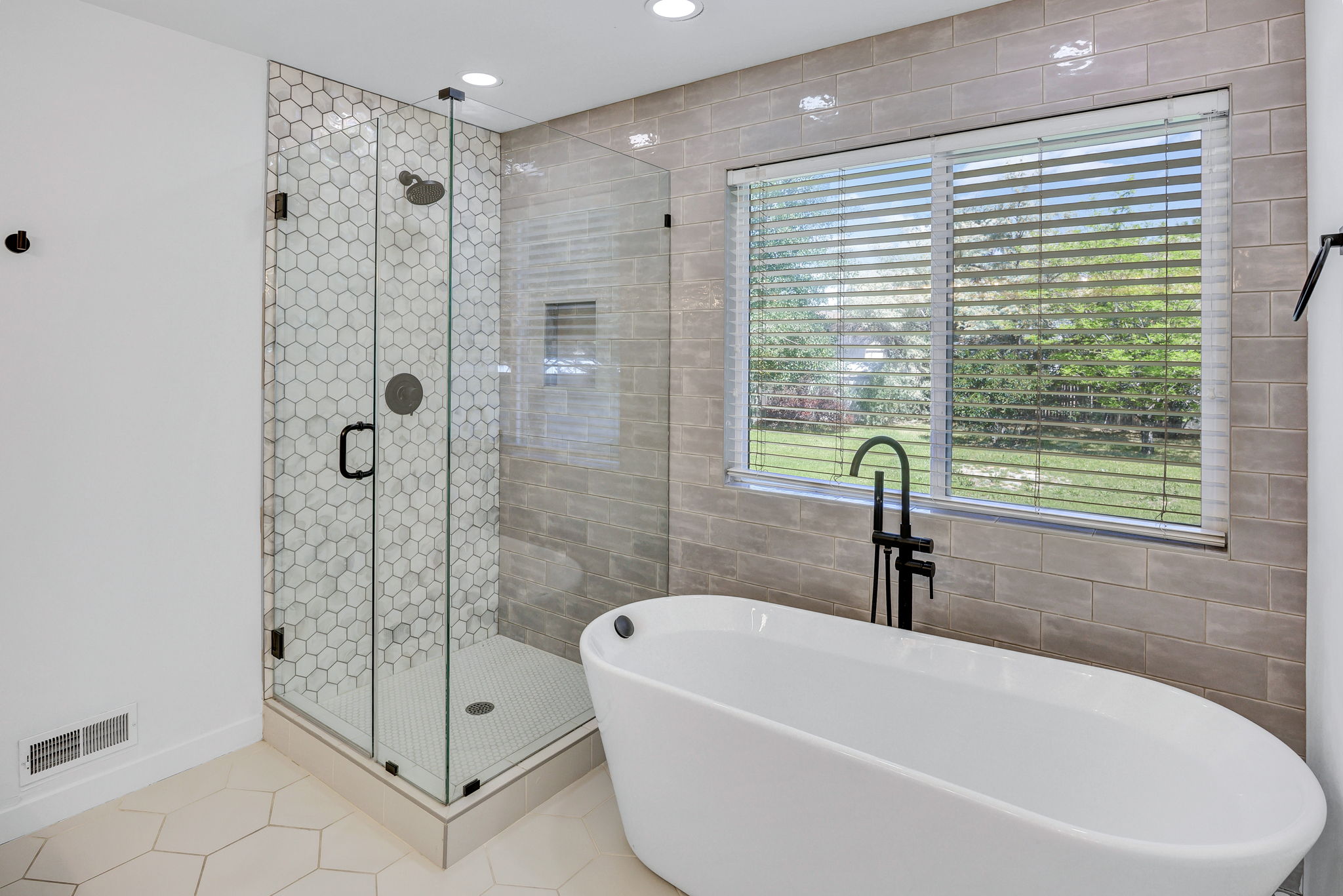 Freestanding soaking tub with a floor-mounted matte black faucet