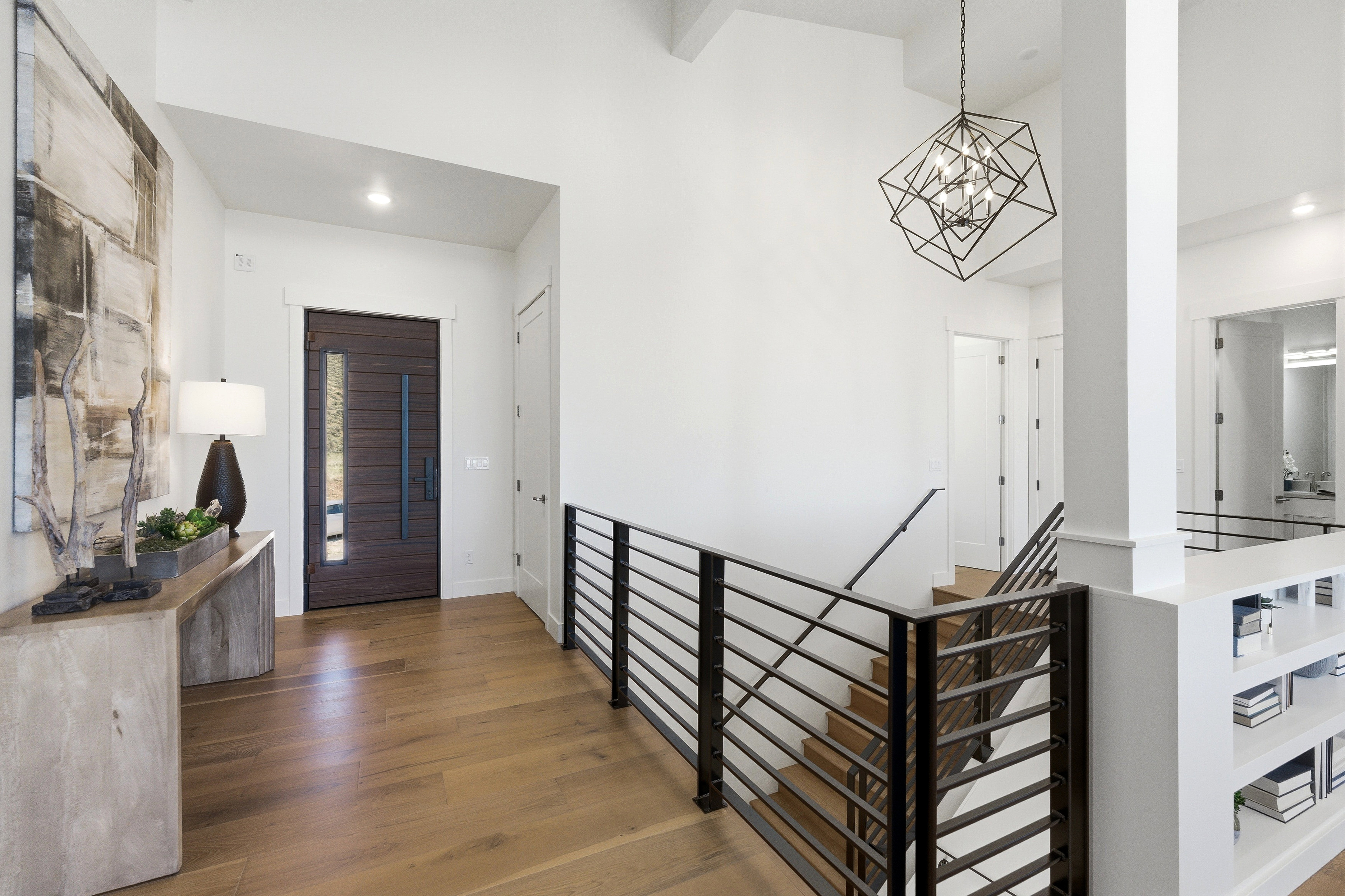 Entry foyer featuring wood-finish flooring and a contemporary dark wood entry door with a frosted glass insert