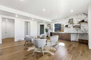 Spacious room featuring wide plank wood-finish flooring, recessed lighting, and white baseboards