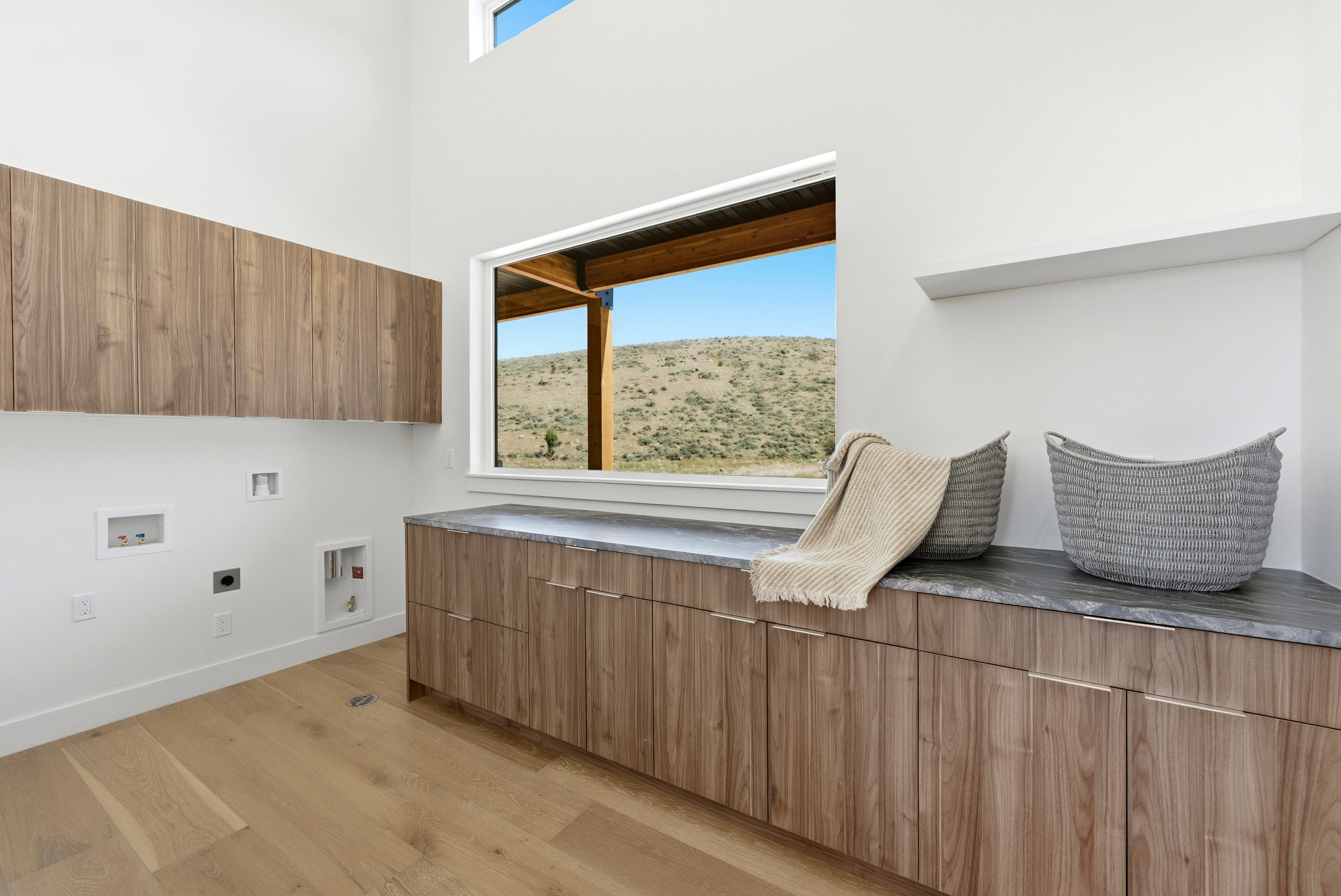 Laundry room featuring light wood-finish flooring, white walls, and a large window