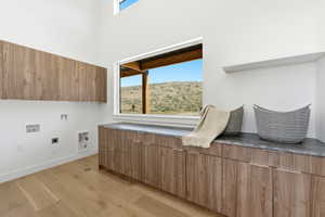 Laundry room featuring light wood-finish flooring, white walls, and a large window
