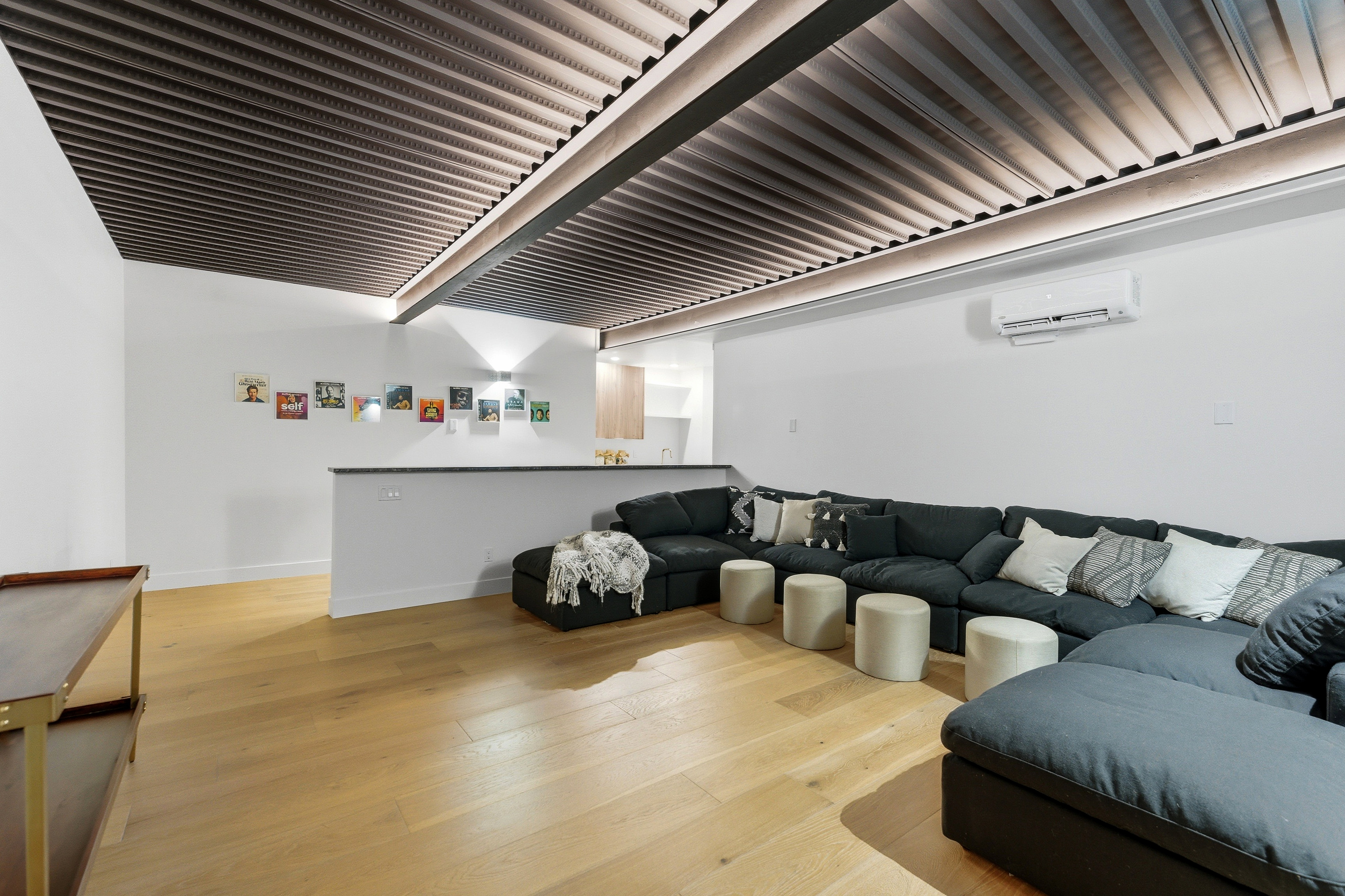 Open-concept living space featuring wood-finish flooring and a distinctive corrugated ceiling with integrated lighting