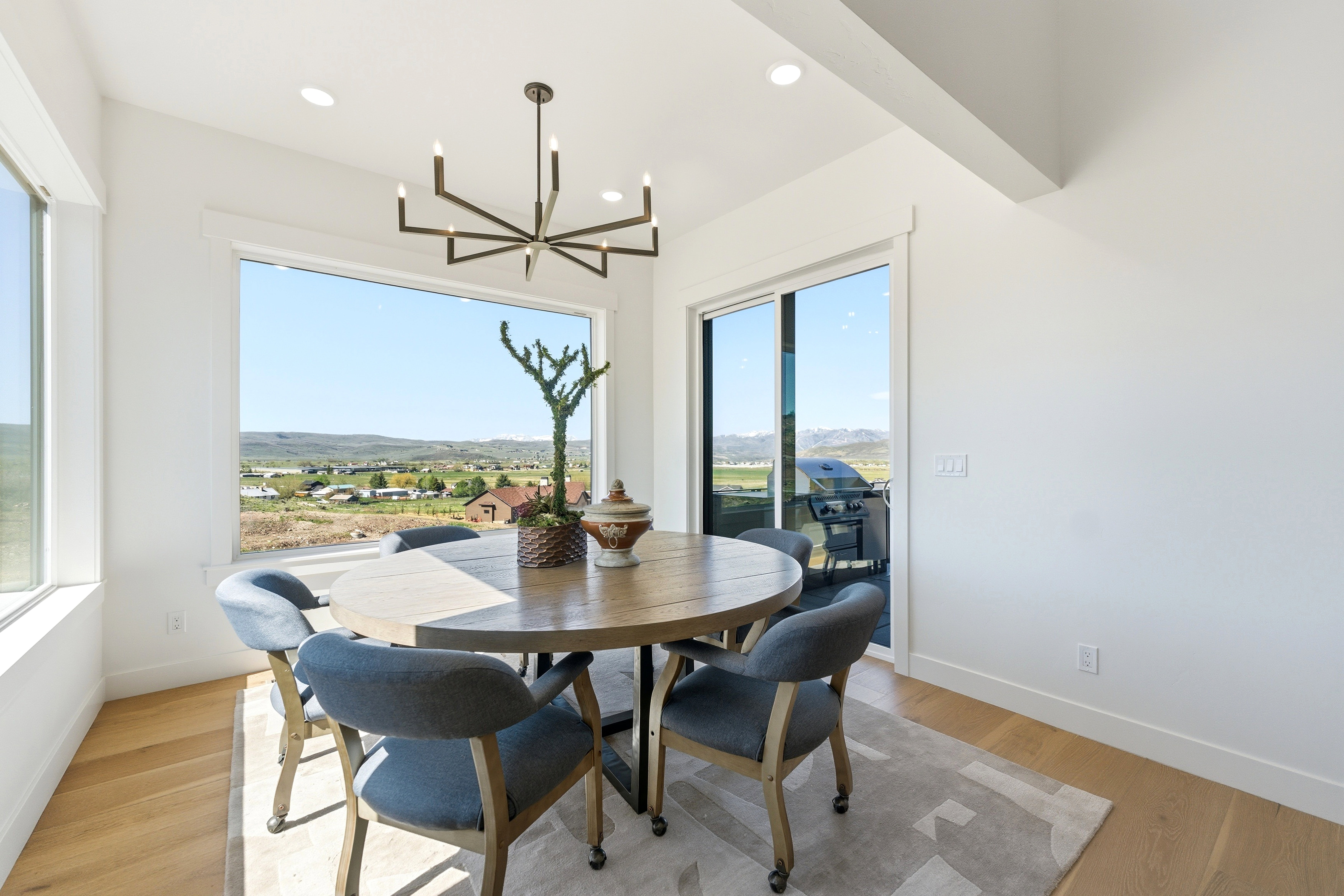 Bright dining area featuring expansive windows, wood-finish flooring, a modern chandelier, and recessed lighting